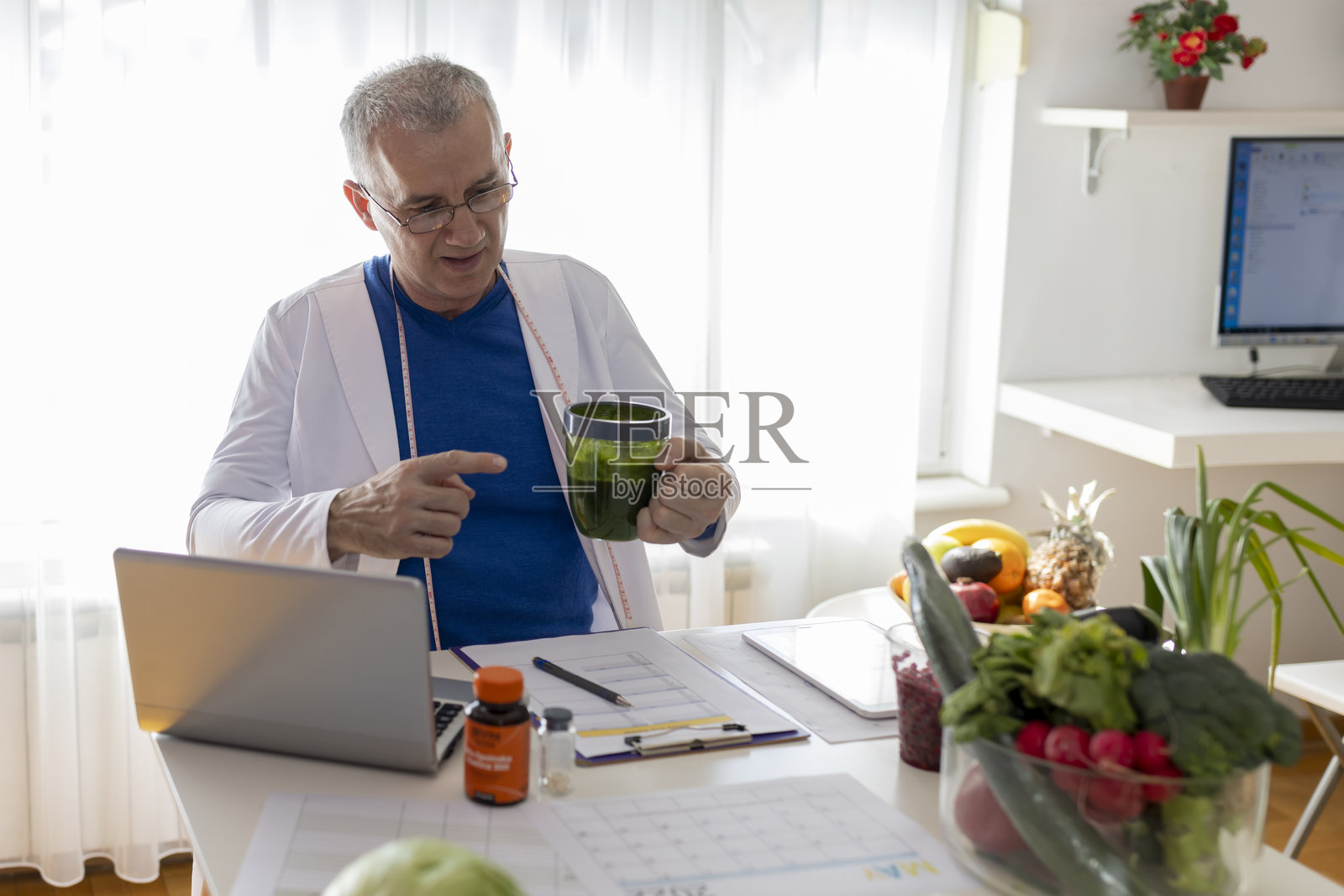 一位经验丰富的男性营养学家在使用笔记本电脑的在线会话中告诉患者排毒冰沙的好处。照片摄影图片
