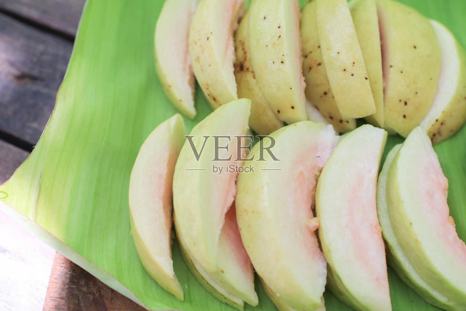 新鲜成熟的番石榴切片,配以甜酱蘸香蕉叶。热带,烹饪,健康的生活方式。照片摄影图片