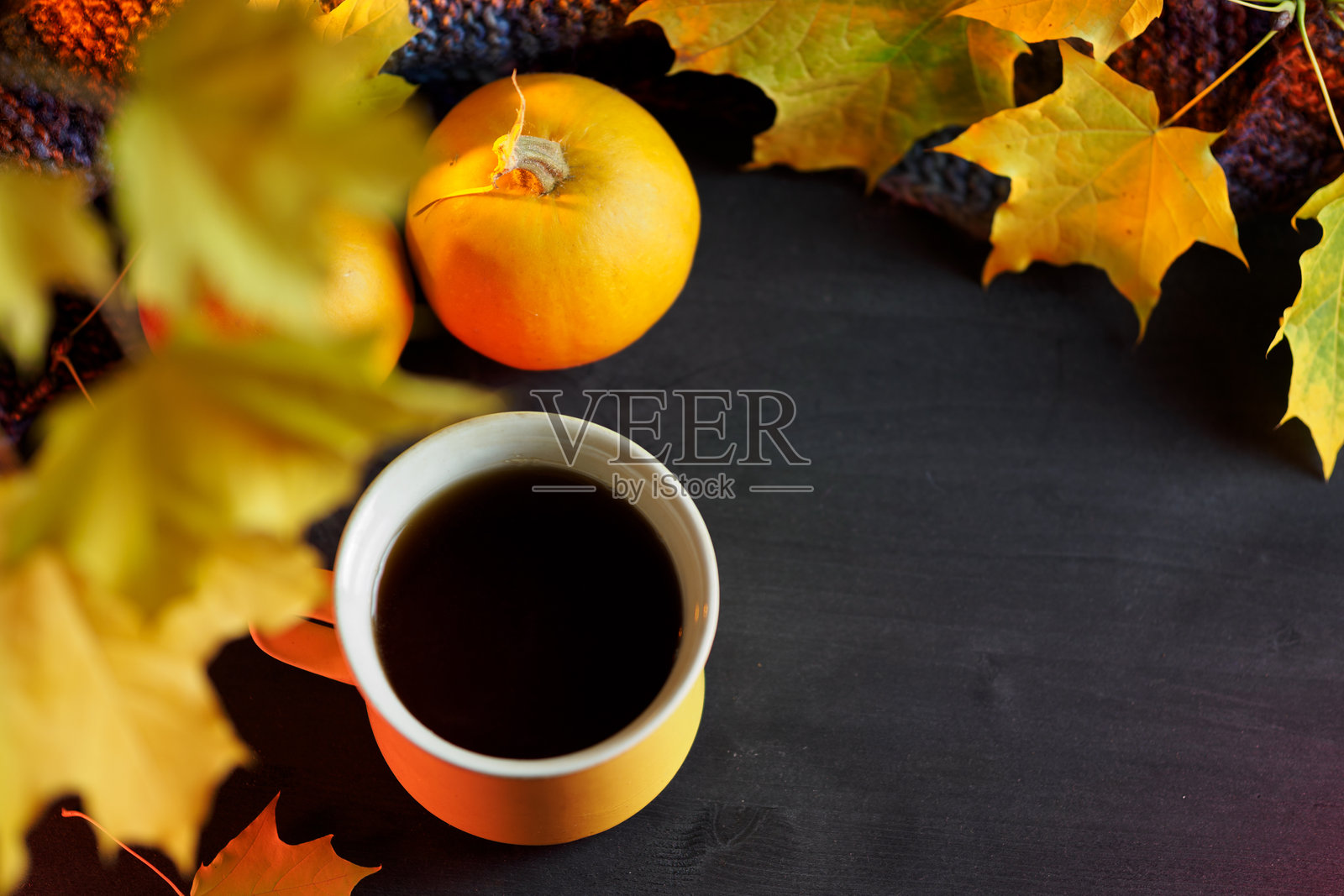 黄色咖啡杯、枫叶、南瓜和针织围巾俯视图,留白照片摄影图片