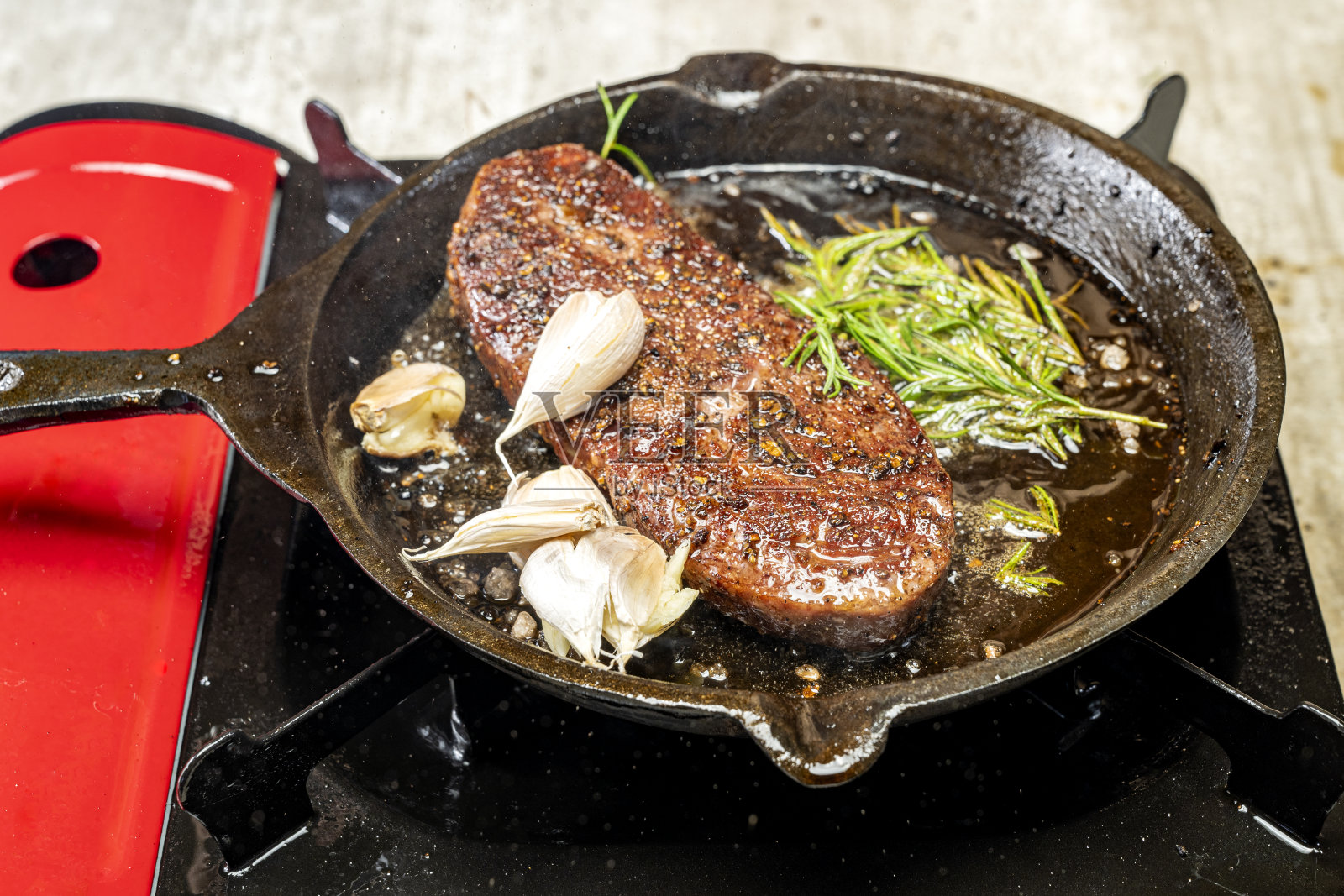 一片西冷肉正在锅里和大蒜和香草一起烹饪照片摄影图片