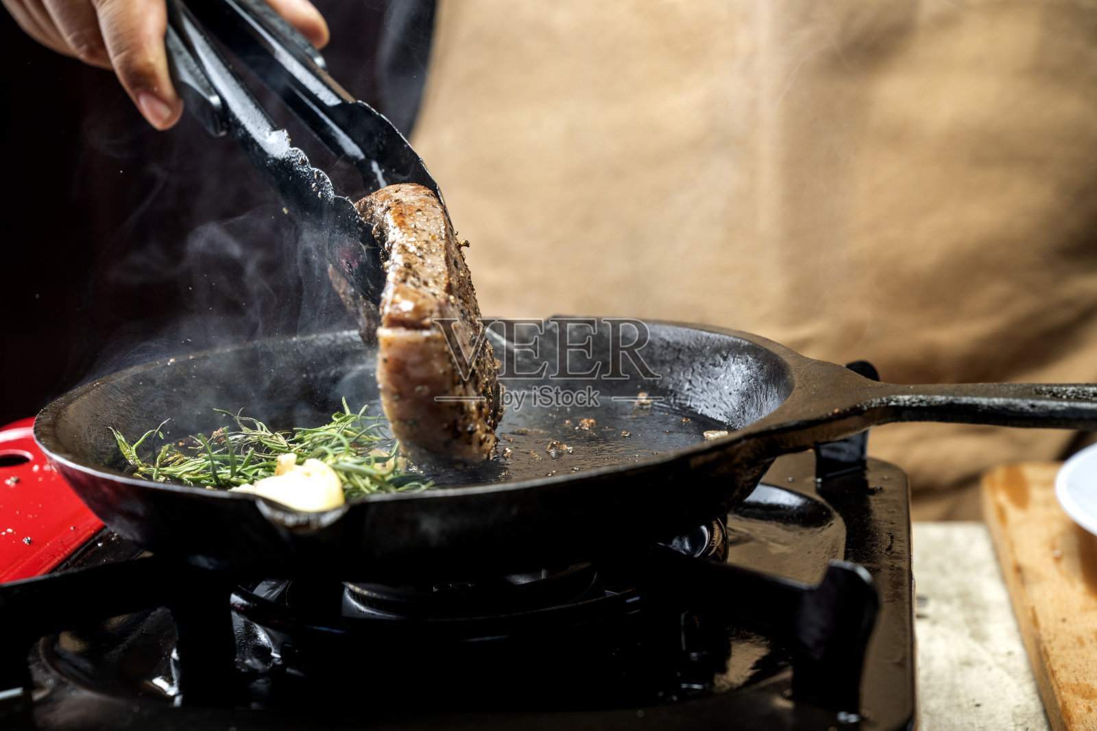 一个人正在炉子上的平底锅里煮皮卡亚牛排照片摄影图片