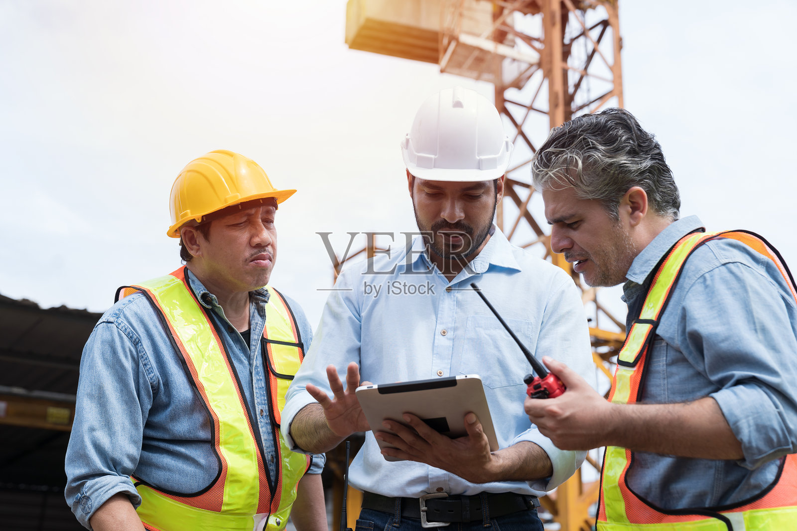 男工程师施工队在施工现场用数码平板讨论建筑结构。一群在建筑工地工作的男性建筑工人照片摄影图片