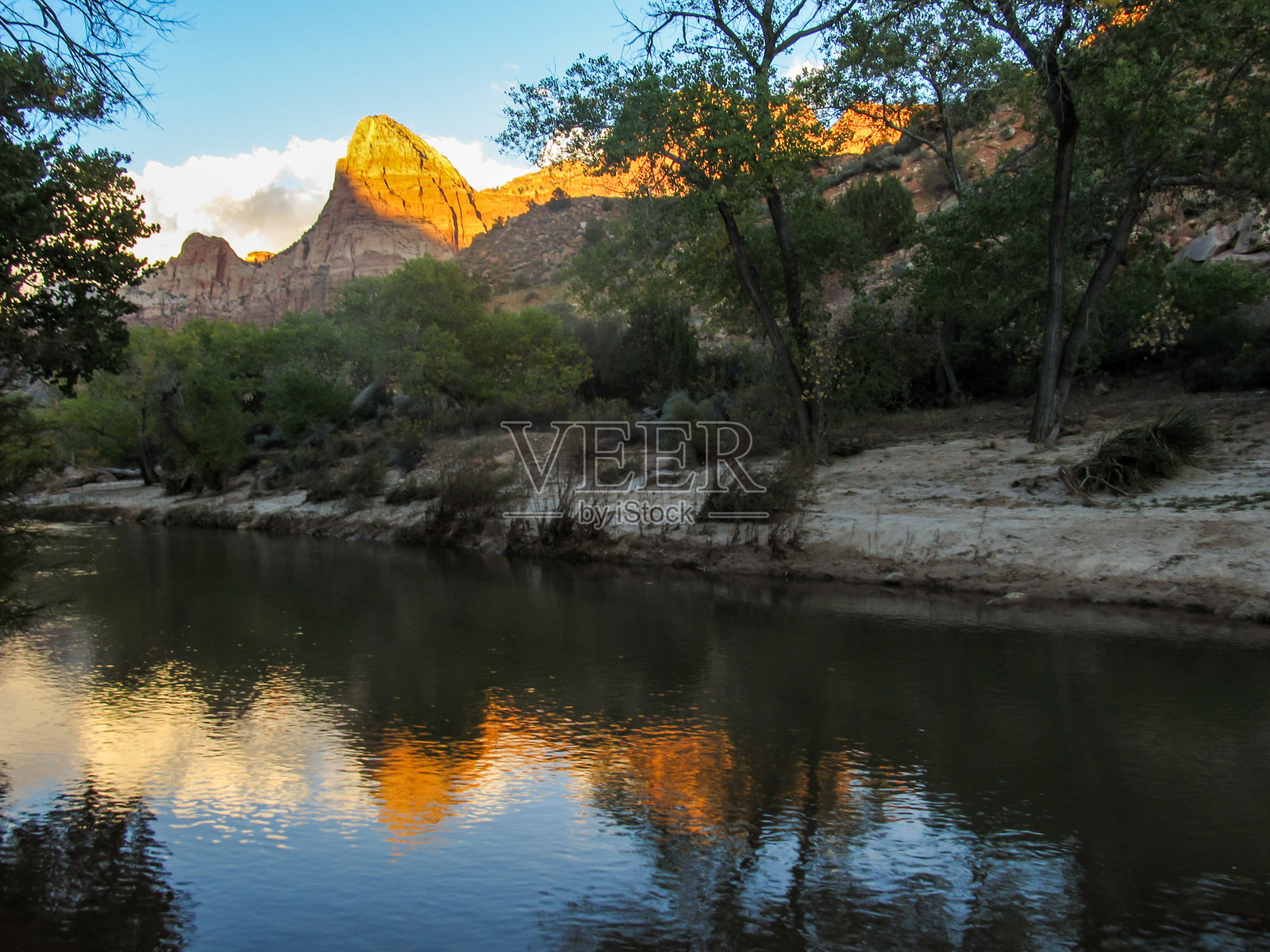 美国犹他州锡安峡谷的守望者耸立在维珍河上,反映出雄伟的山峰,在傍晚的金色阳光下。锡安国家公园最初是Mukuntuweap国家纪念碑,于1919年宣布成立,这使它成为世界上最古老的国家公园照片摄影图片