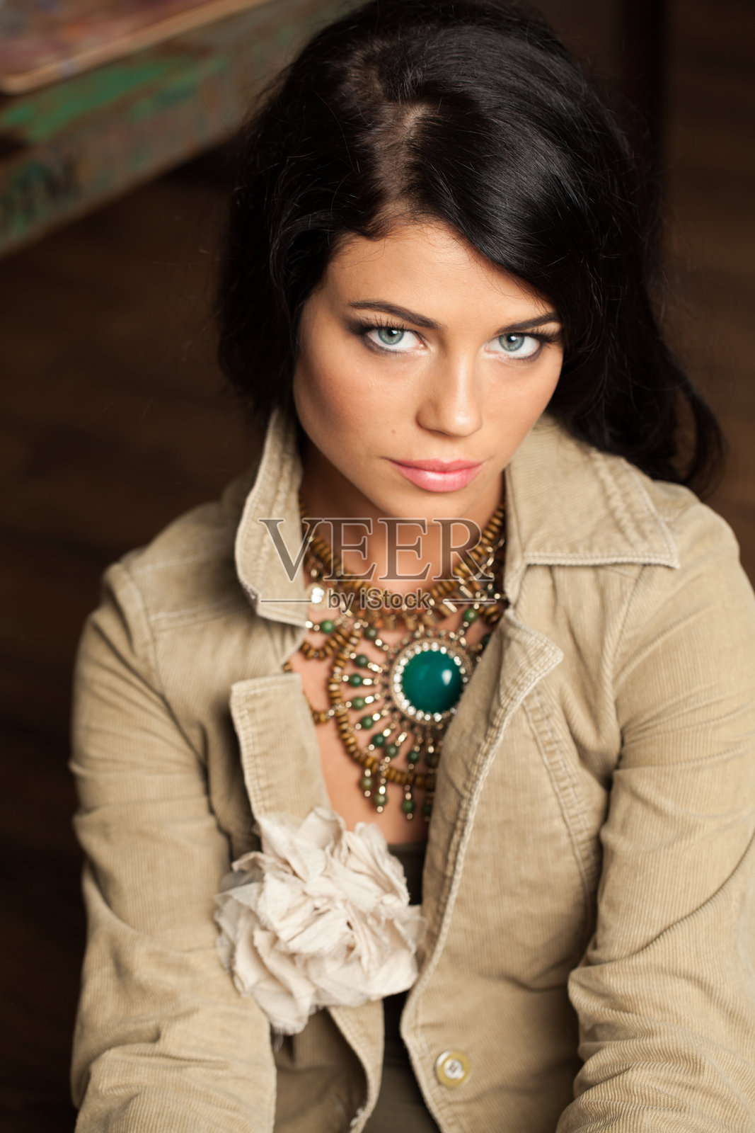 迷人的黑发女人在艺术工作室里摆姿势。年轻的女士长卷发和化妆在室内棕色背景照片摄影图片