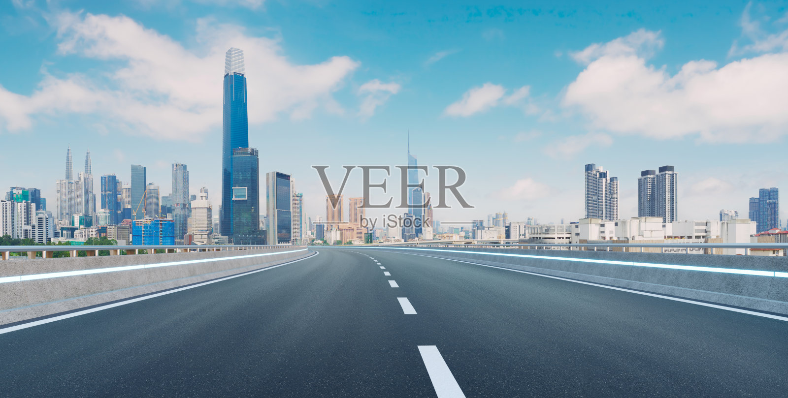 空旷的沥青道路与蓝天下的现代城市天际线全景照片摄影图片