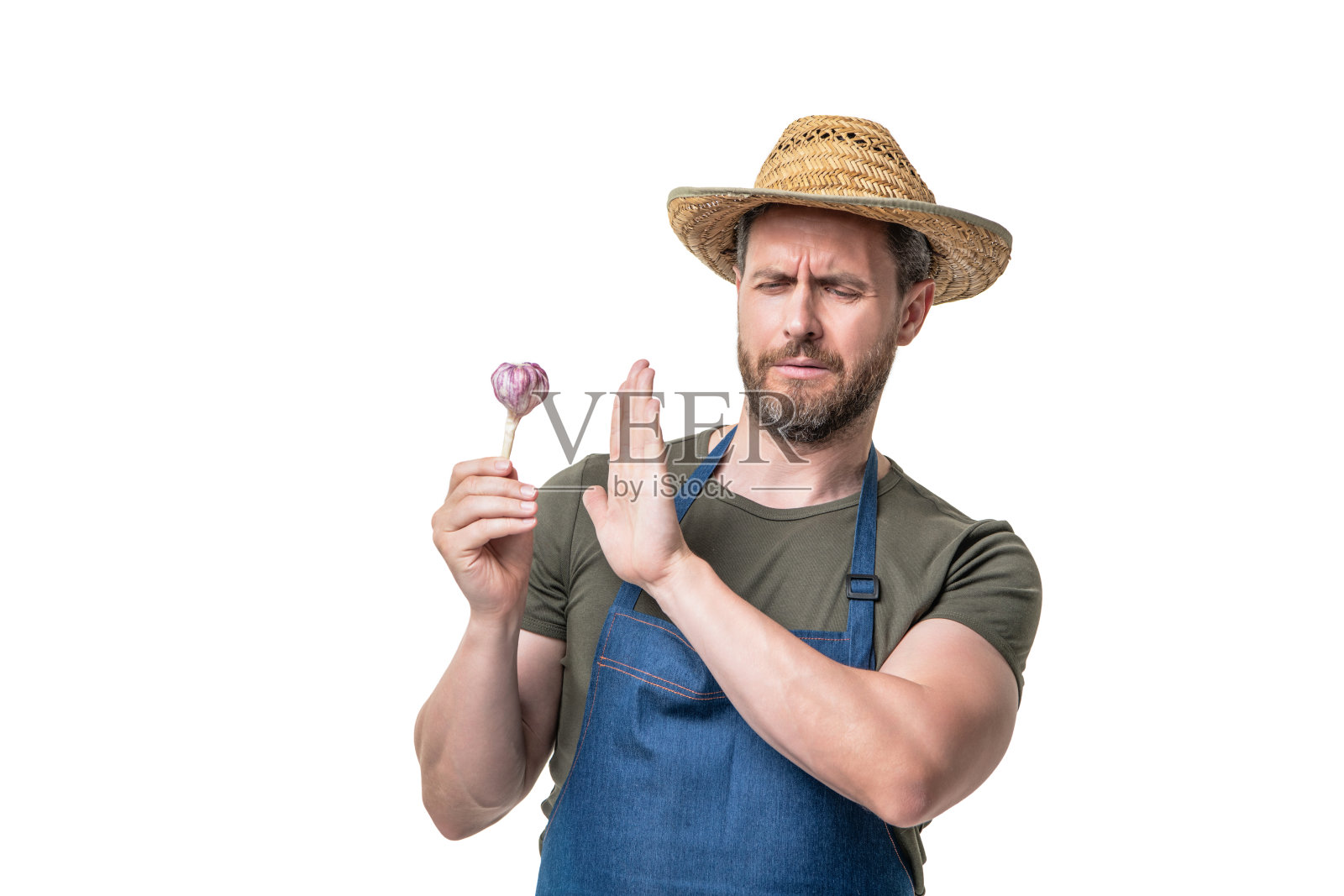 穿着围裙,戴着帽子的男人,戴着大蒜蔬菜,孤立在白色的衣服上。不好的气味照片摄影图片