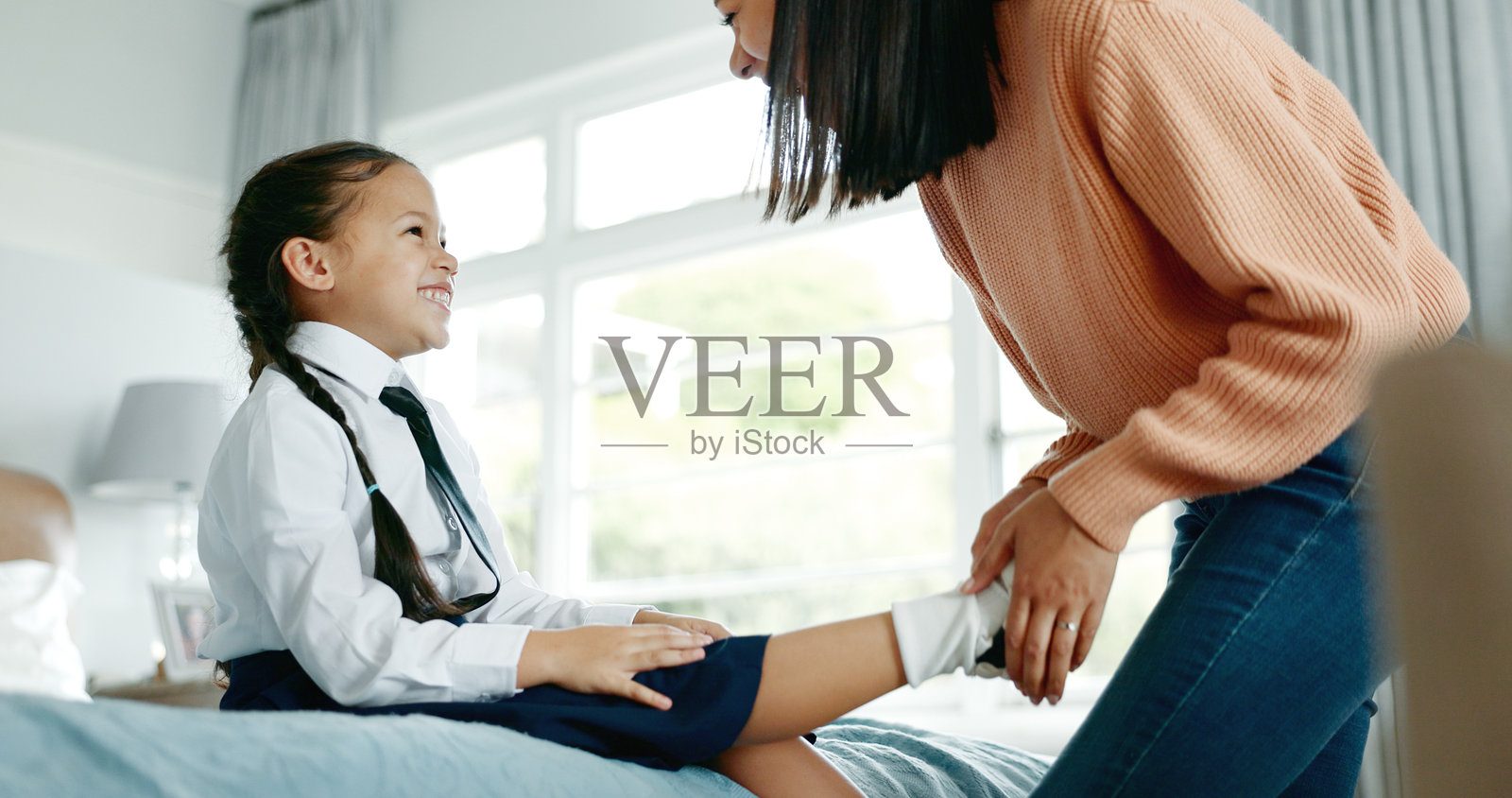 早晨,校服和妈妈带着女孩,家和幸福带着爱,亲情和牵挂在一起。公寓,床,单亲妈妈和女儿,妈妈和孩子穿鞋,兴奋和帮助照片摄影图片