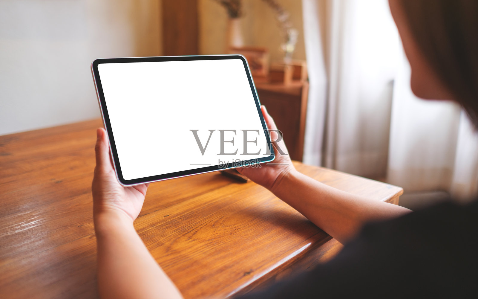 一位女性在家中手持数字平板,桌面屏幕为空白的模拟图像照片摄影图片