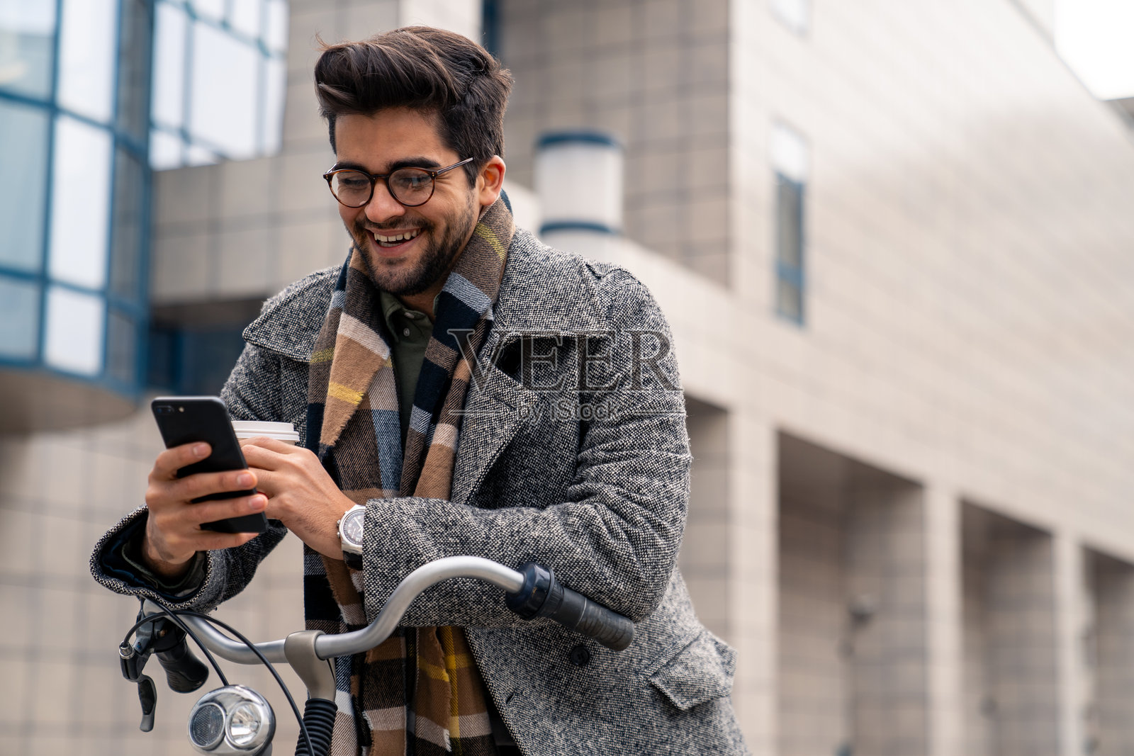 骑自行车在办公室外查看智能手机的微笑男商人照片摄影图片