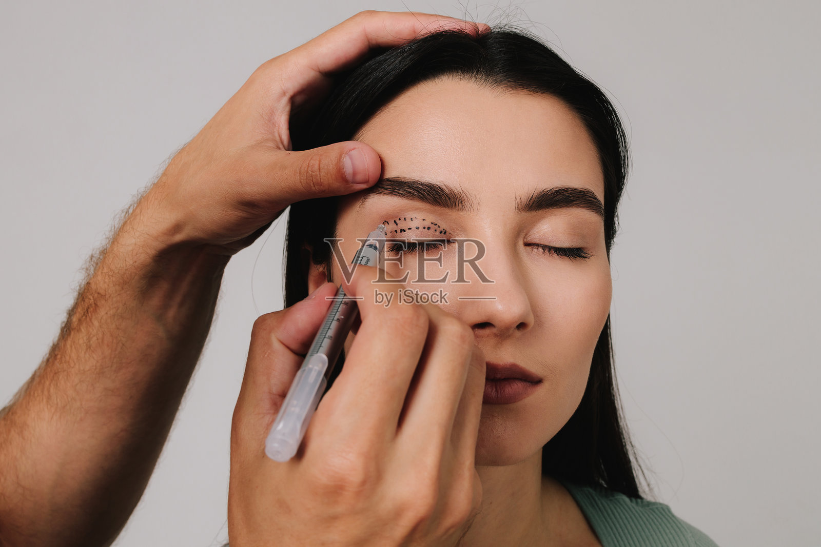 医生正在用医用标记笔绘制上眼睑手术的计划,进行精确的眼睑提升标记。照片摄影图片