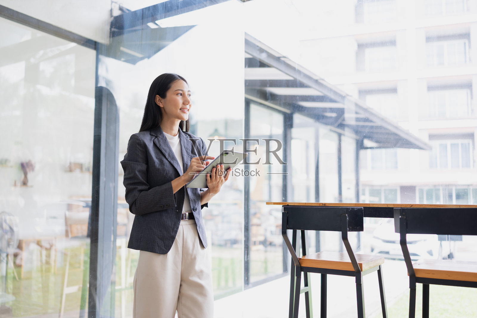 微笑的亚洲女性在办公室里手持平板电脑。照片摄影图片