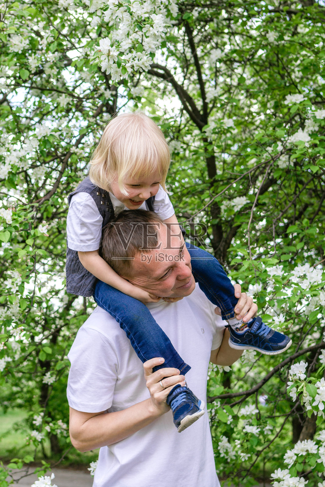 父亲和儿子在美丽的花园里享受美好的春日时光。照片摄影图片