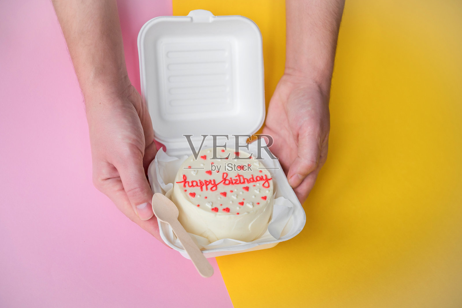 一个男人的手拿着一个节日便当蛋糕,上面有生日和心形装饰。照片摄影图片