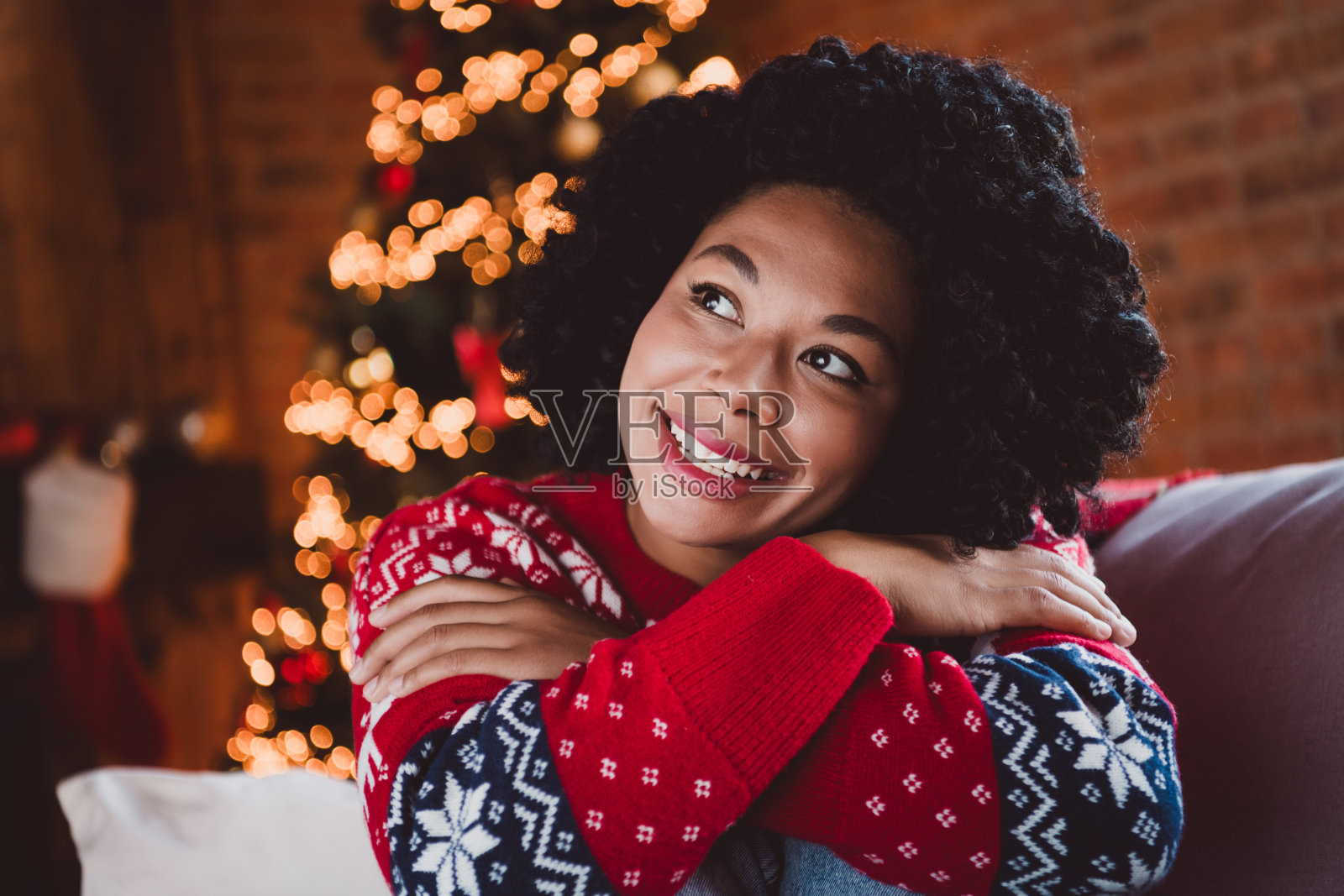 漂亮年轻女孩凝视梦幻的空旷空间,穿着红色圣诞服装,享受现代舒适的圣诞派对装饰,室内公寓环境。照片摄影图片