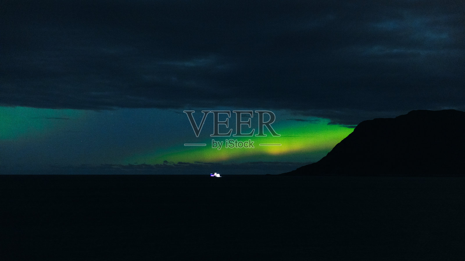 在壮丽的北极光下,船只在夜海中航行照片摄影图片