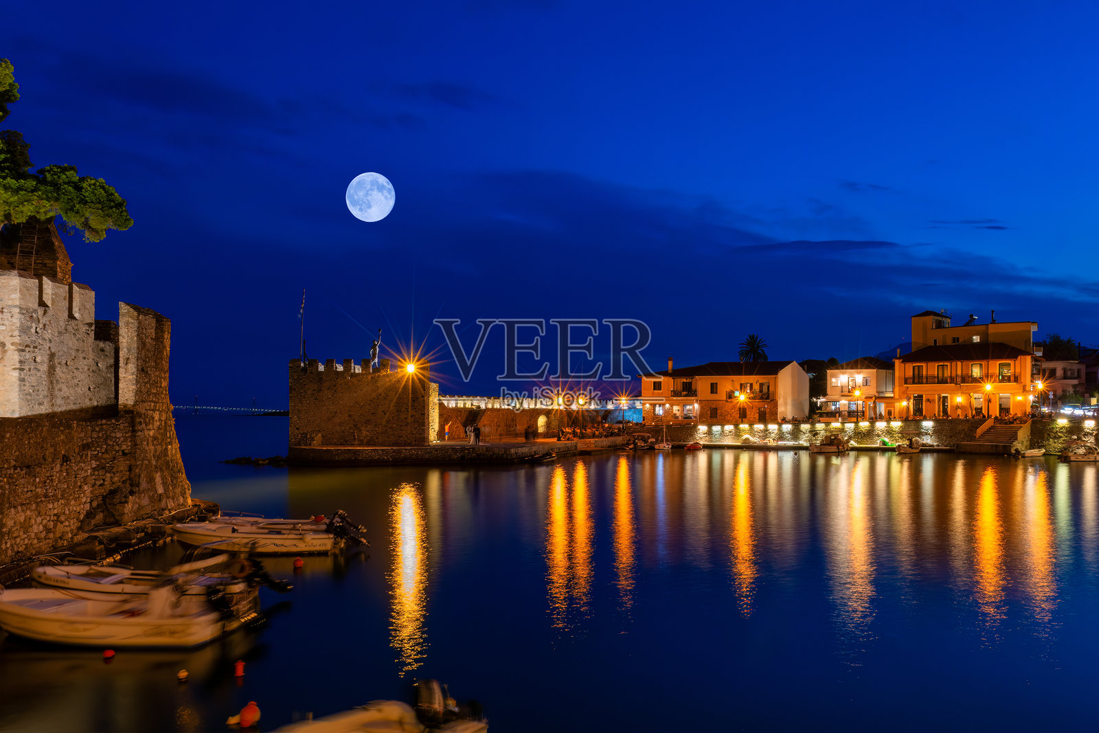 希腊纳夫帕克托斯港口在满月下水面反射的灯光。照片摄影图片