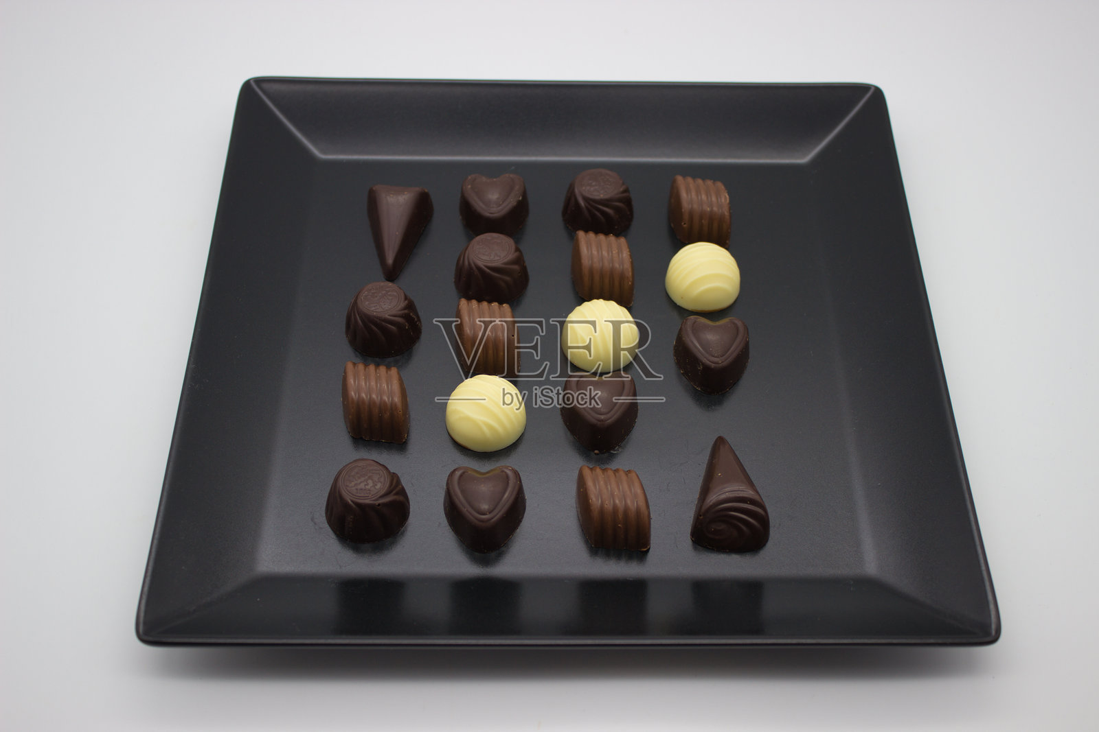 精美的黑色盘子上摆放着各种巧克力。照片摄影图片