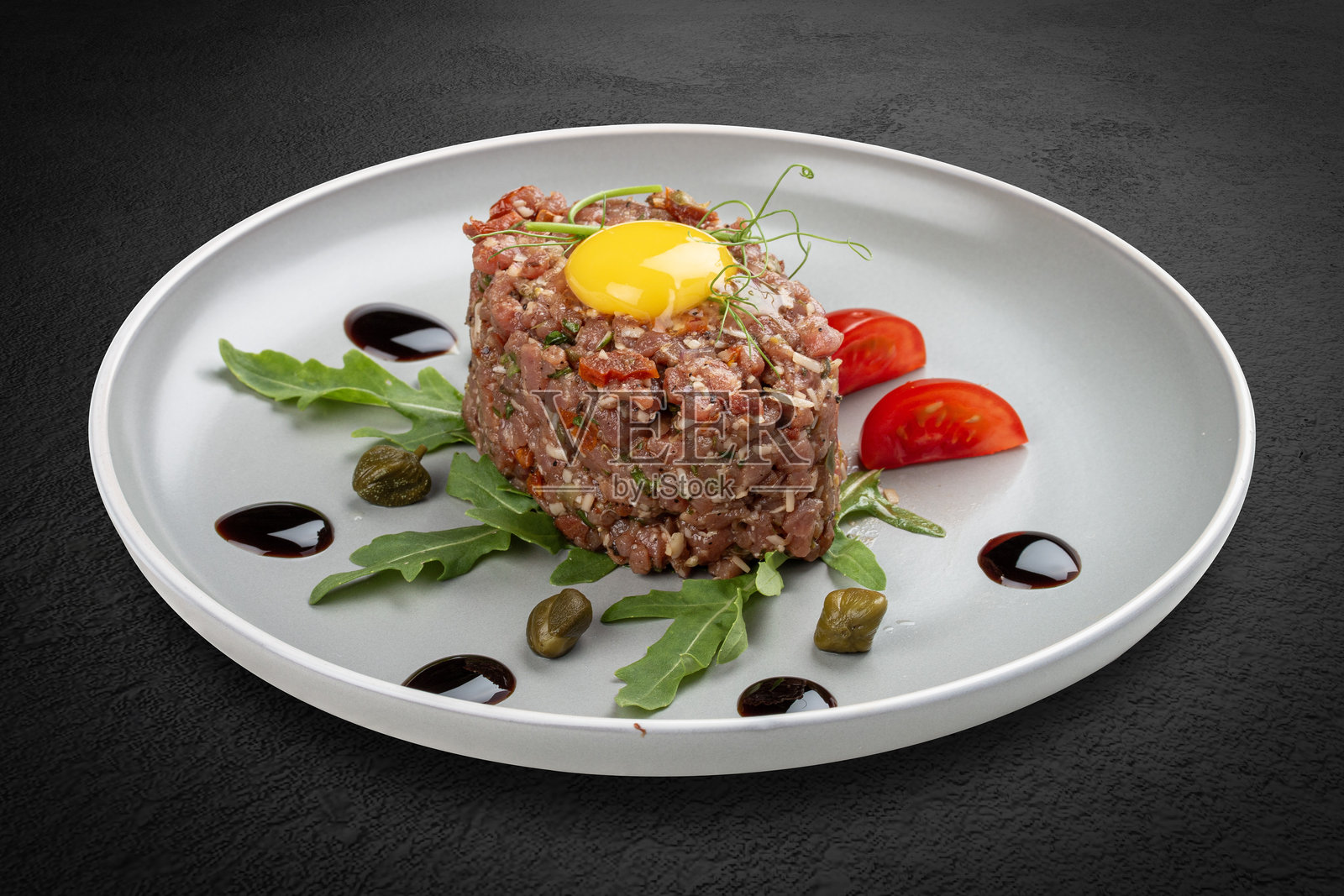 新鲜的小牛肉塔塔配以番茄和芝麻菜。照片摄影图片