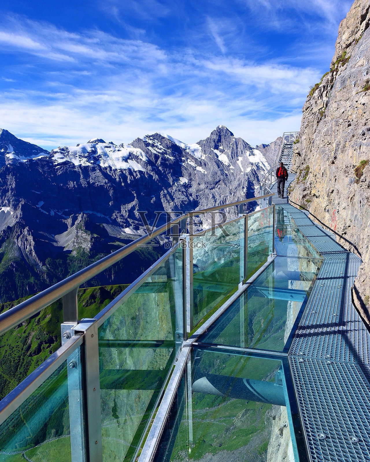 背影男子在施尔特霍恩的步道上行走,背景是山脉。照片摄影图片