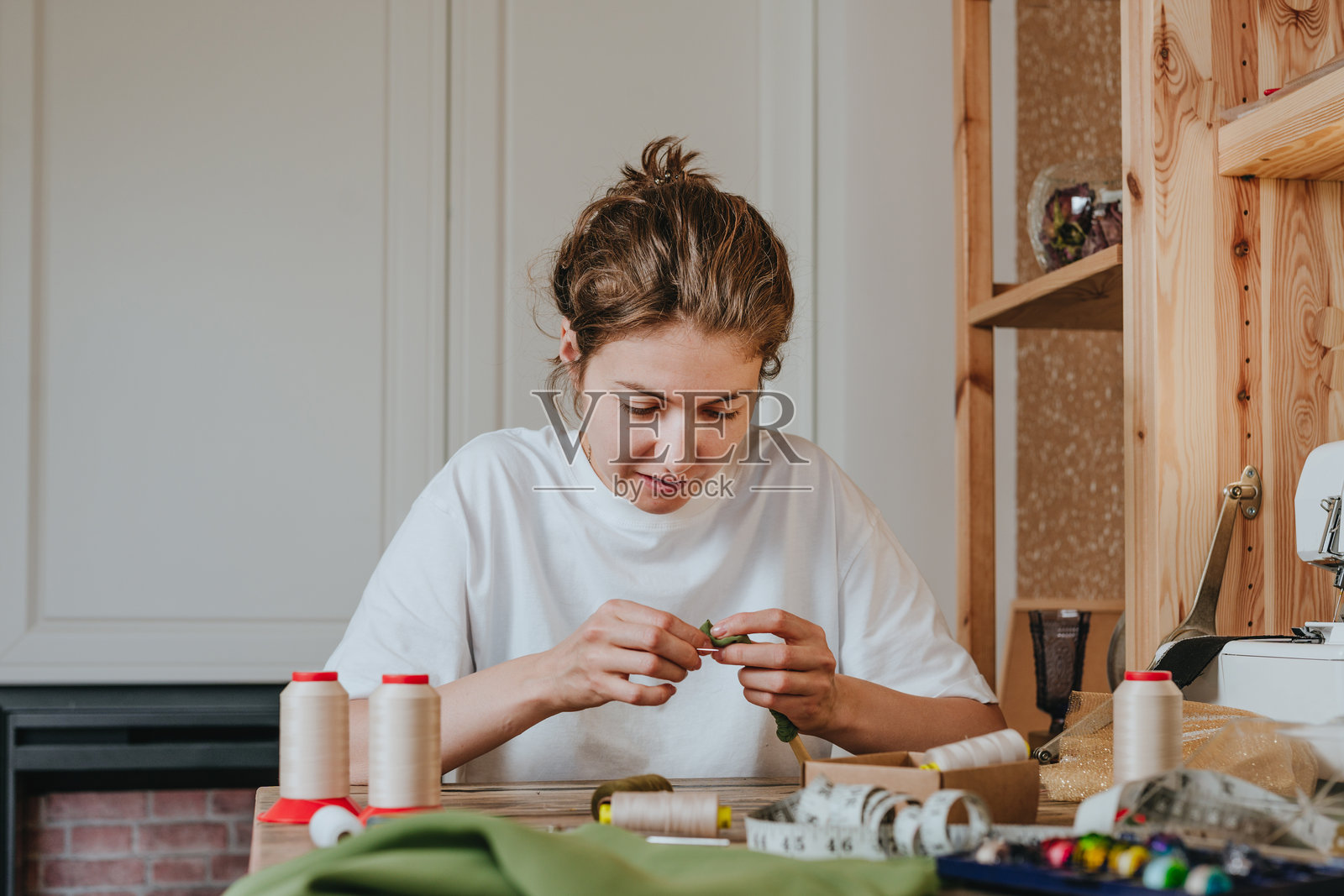 女性裁缝坐在桌子旁边缝纫机前缝纫照片摄影图片