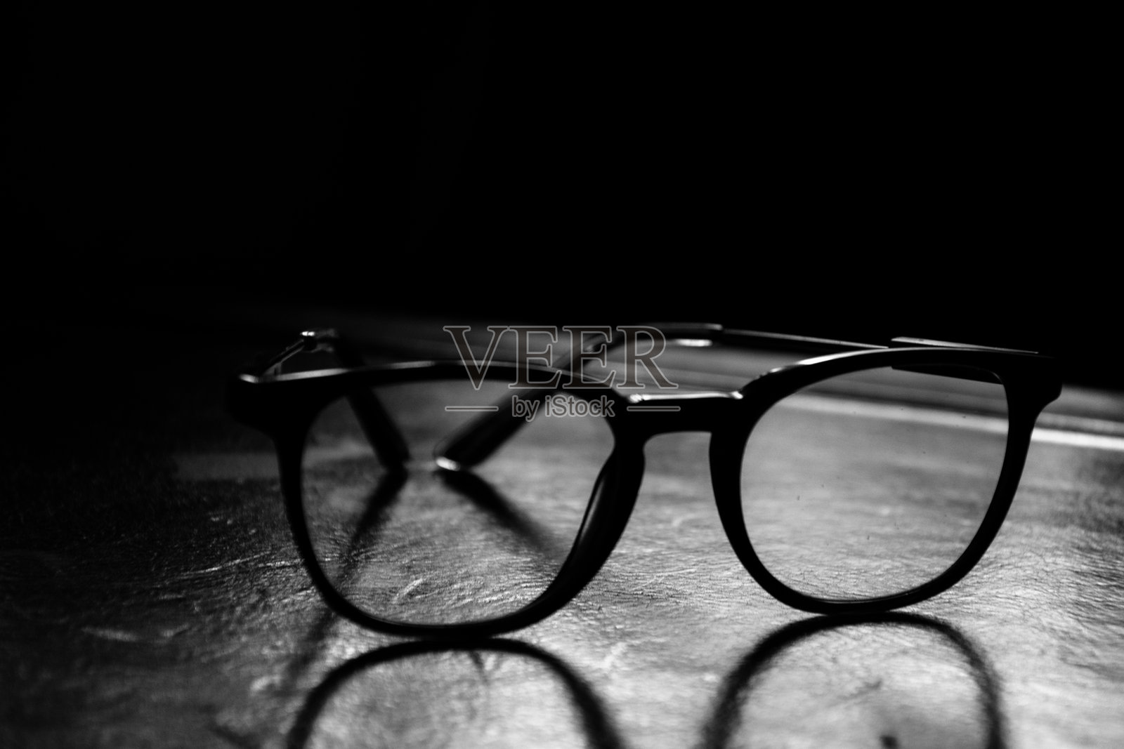 黑白眼镜放在奢华的皮革桌子上,特写。照片摄影图片