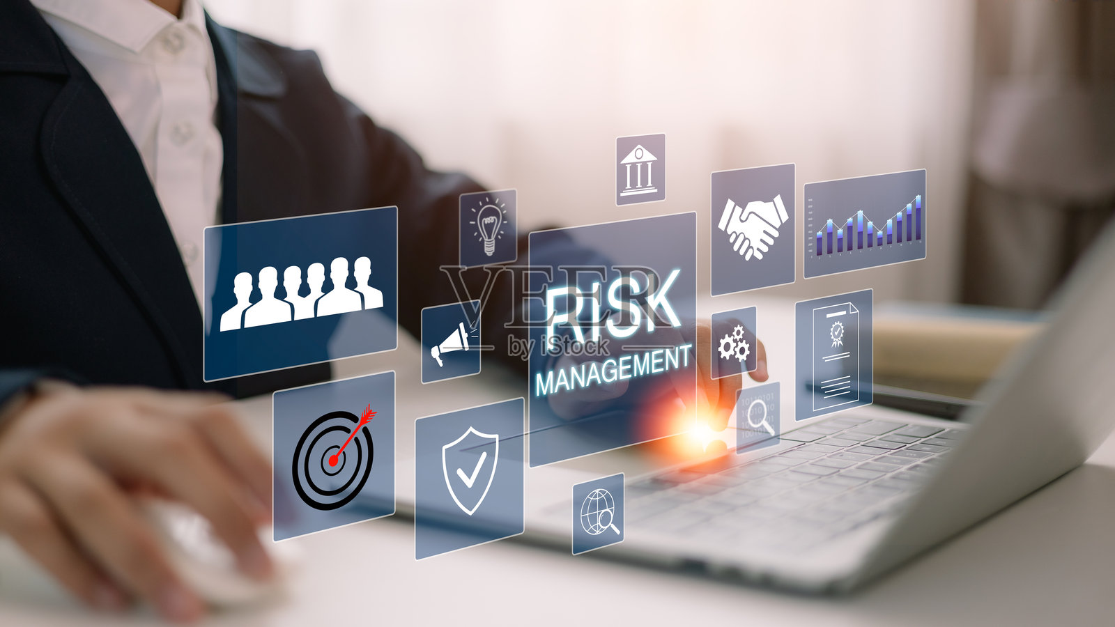 一位商人在笔记本电脑屏幕上分析一个虚拟风险管理界面,界面上有关键策略图标。企业风险管理策略概念。分析风险评估,财务分析。照片摄影图片