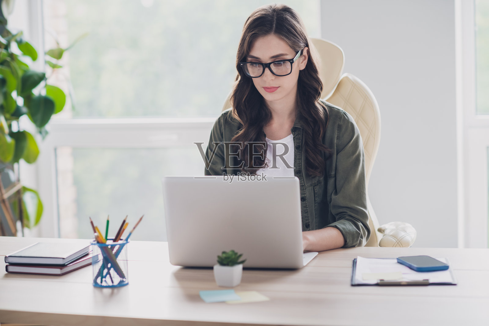 微笑的快乐女交易员戴着眼镜,在室内工作站与现代设备交流照片摄影图片