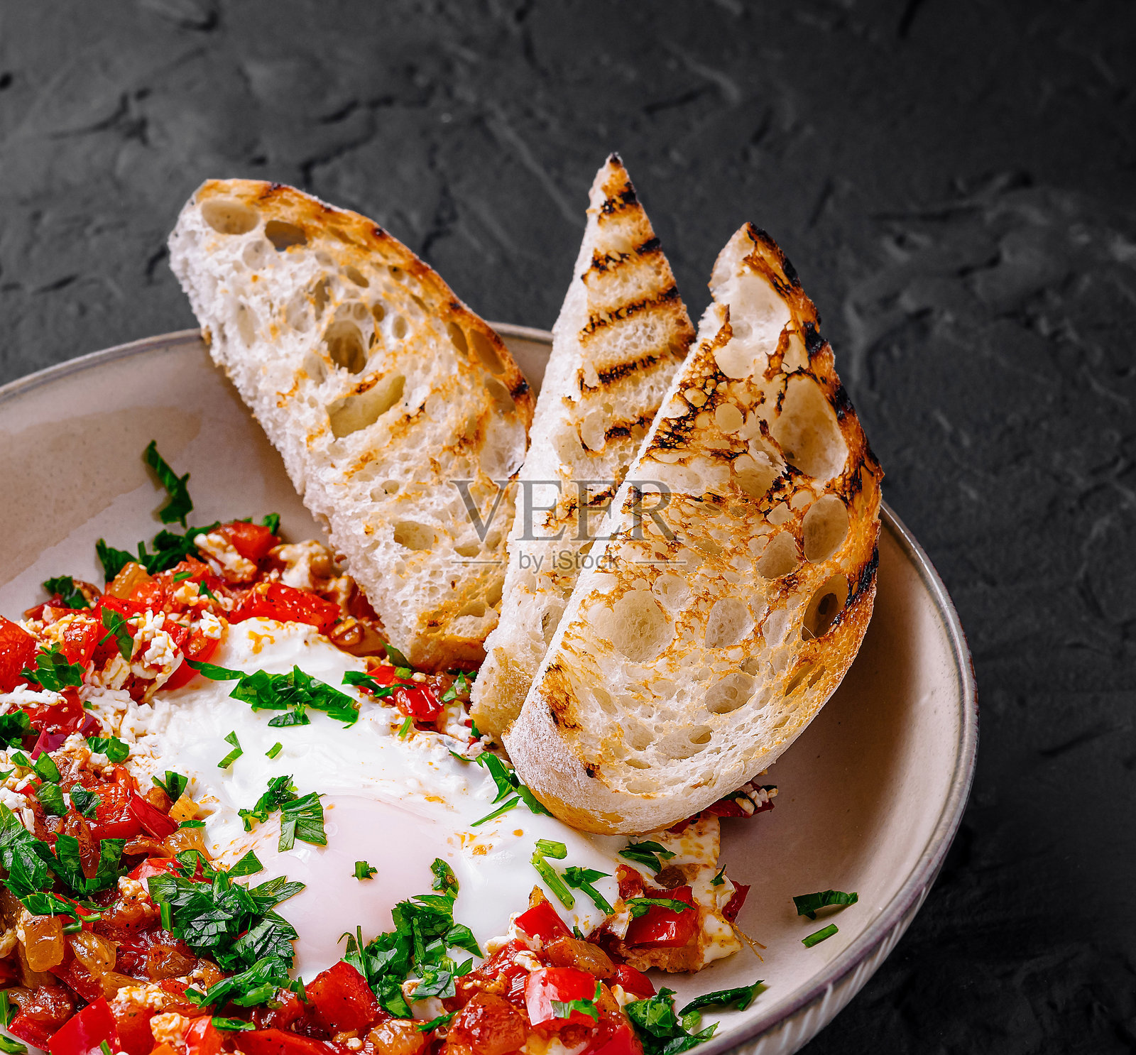 美味的沙克舒卡配烤面包,背景为深色照片摄影图片