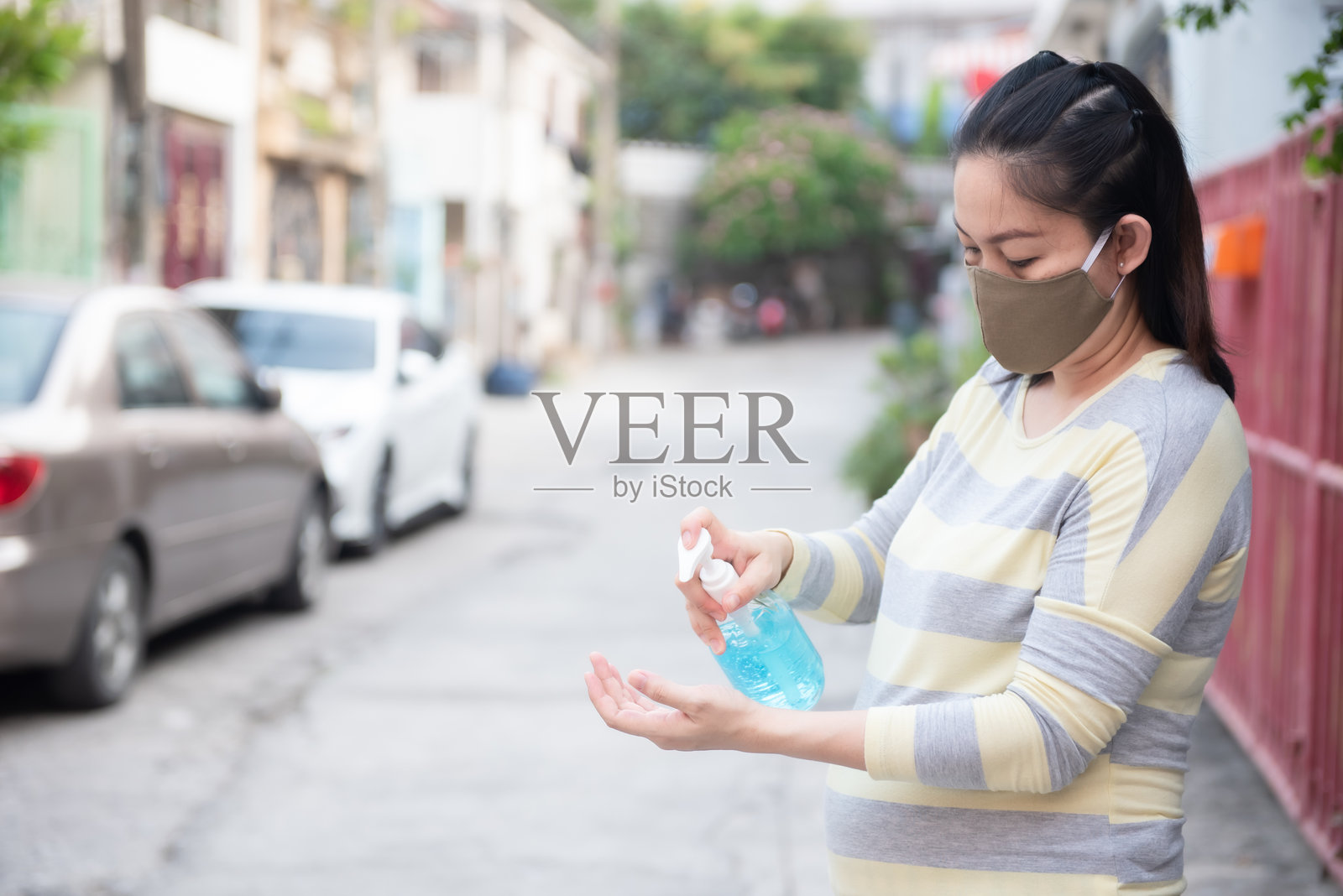 戴口罩的妇女站在马路上用消毒液洗手照片摄影图片