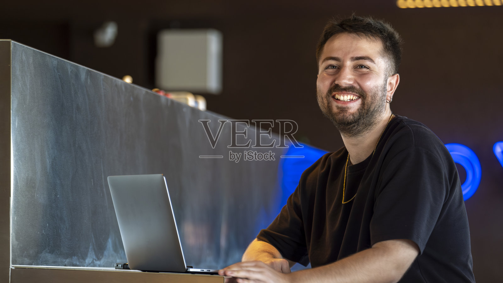 一位年轻的黑发商人在咖啡馆里使用笔记本电脑工作,收到消息后兴奋地庆祝。照片摄影图片