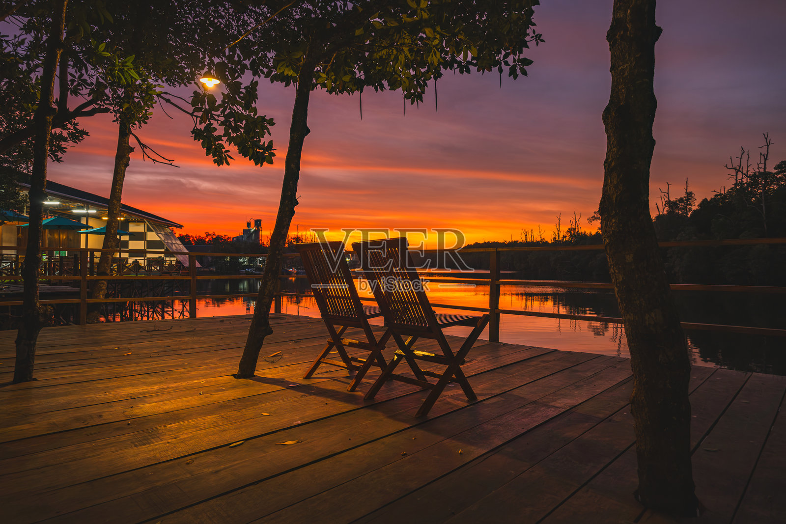 温柔日落时分,河边的两把椅子。照片摄影图片