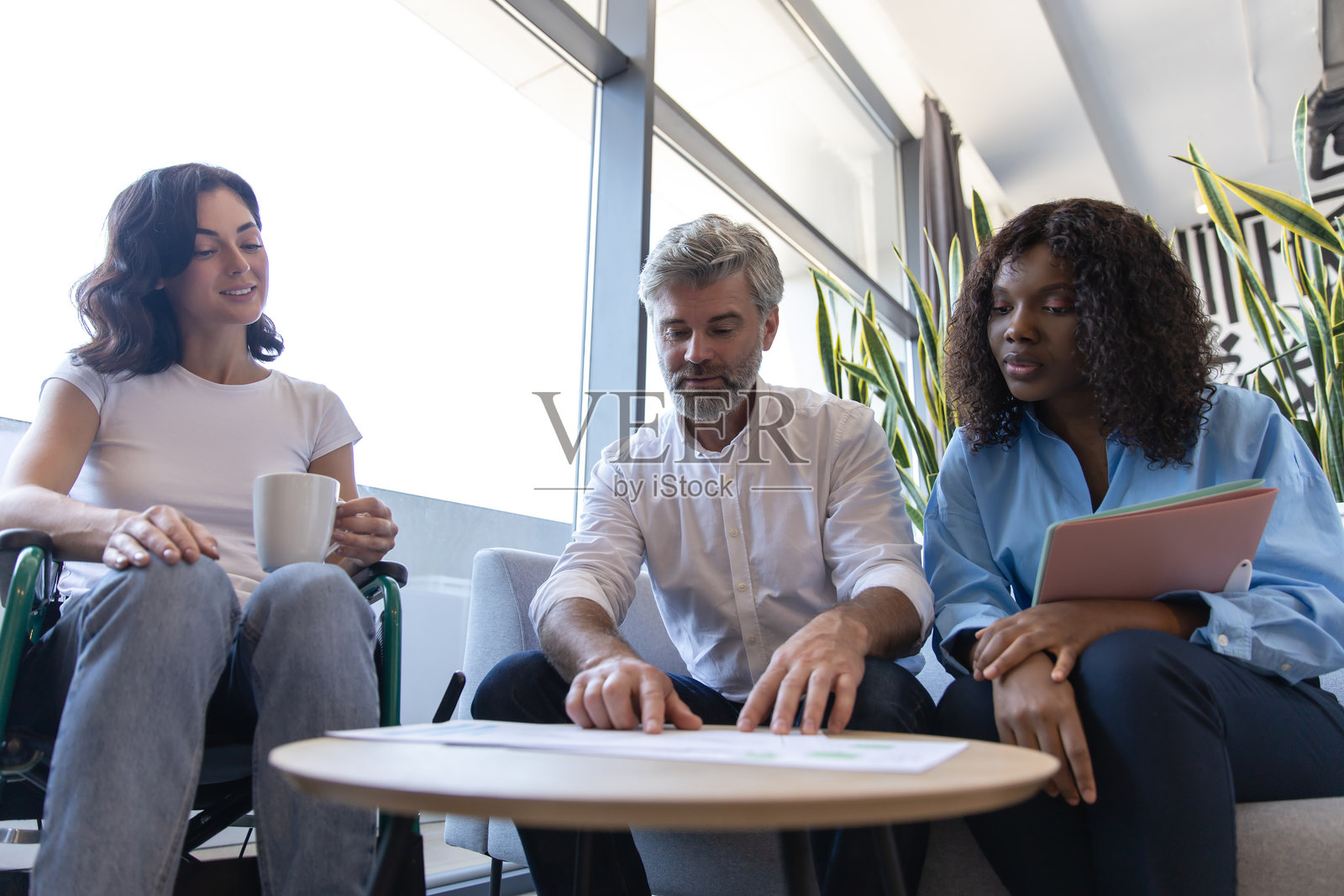 多元化团队在工作场所,包括一位坐轮椅的女性,共同协作制定商业策略照片摄影图片