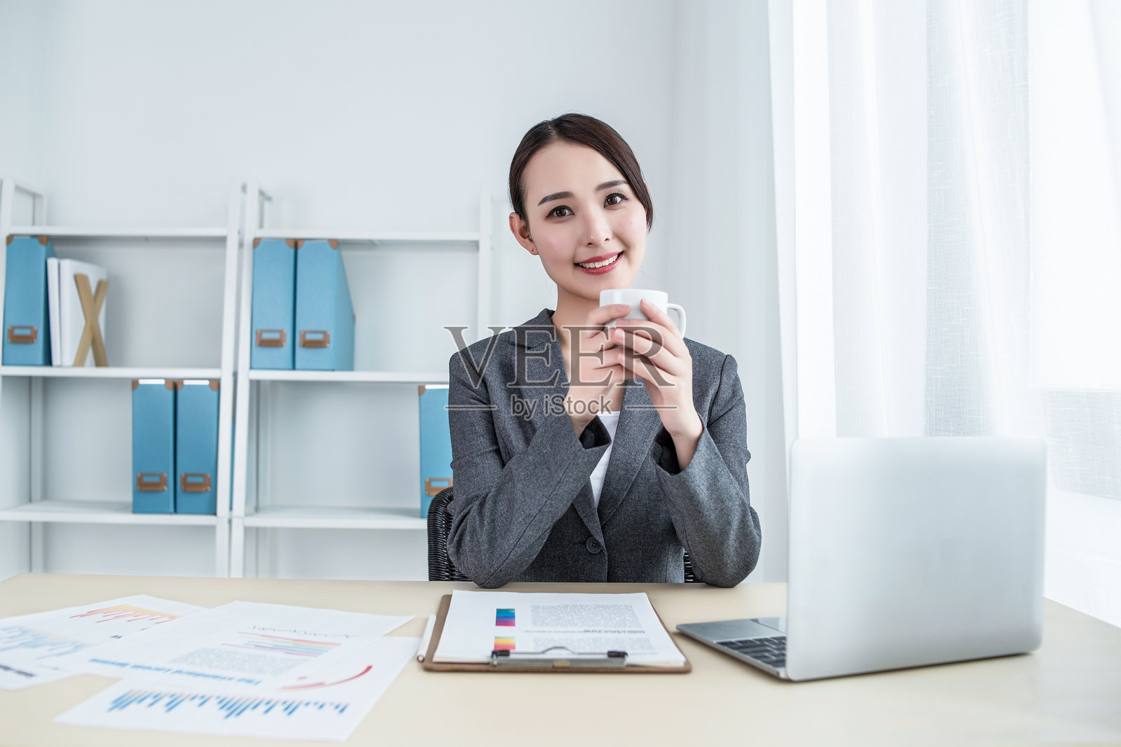 女商人坐在办公室大厅的桌旁,使用笔记本电脑照片摄影图片