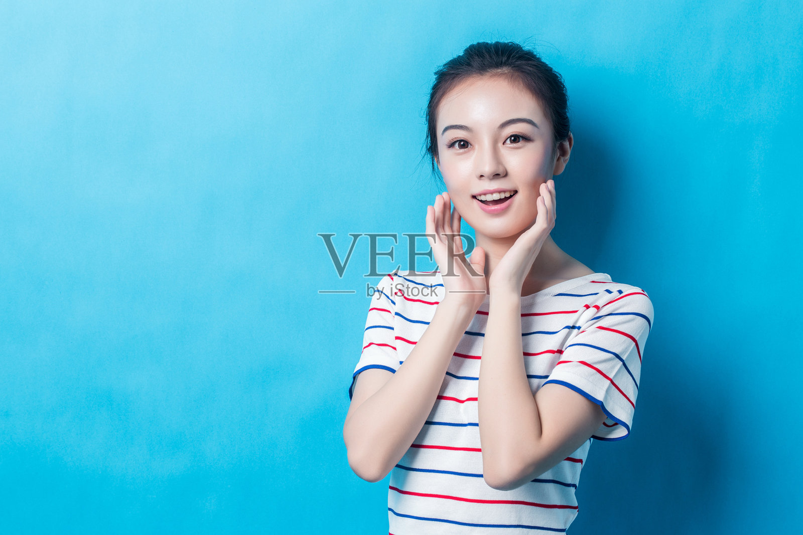 穿着时尚休闲服装的女孩在蓝色背景下大笑照片摄影图片