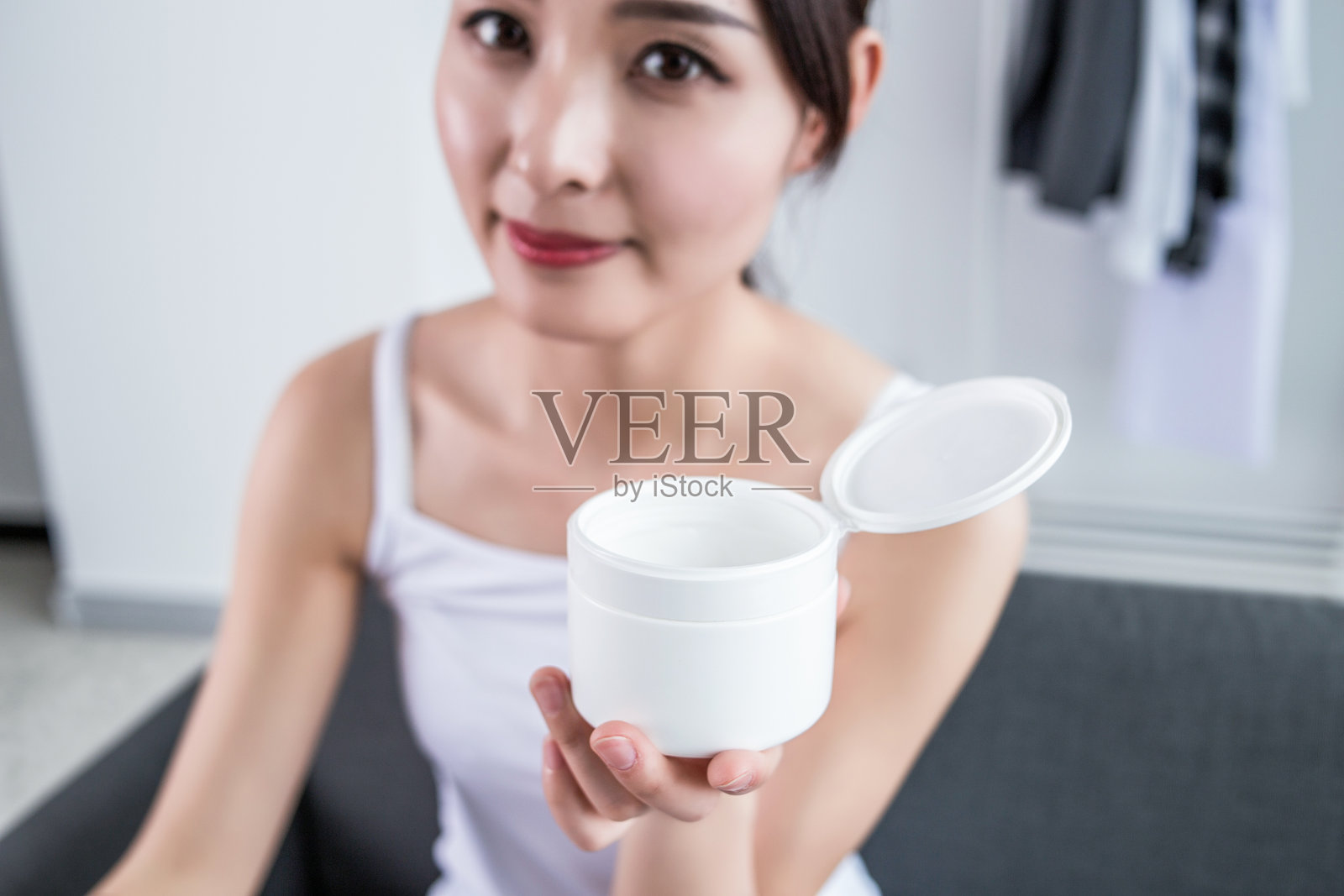 微笑的年轻女性在白色背景下给手涂抹护手霜。照片摄影图片