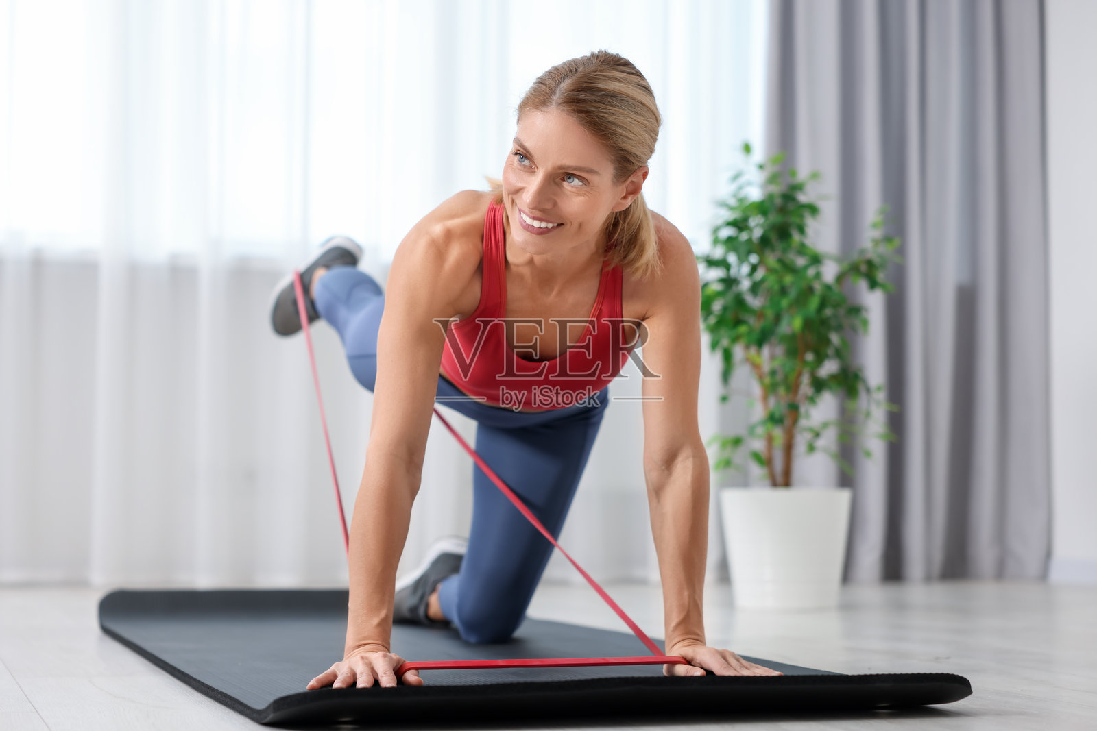 在家用弹力带在垫子上做运动的健壮女人照片摄影图片