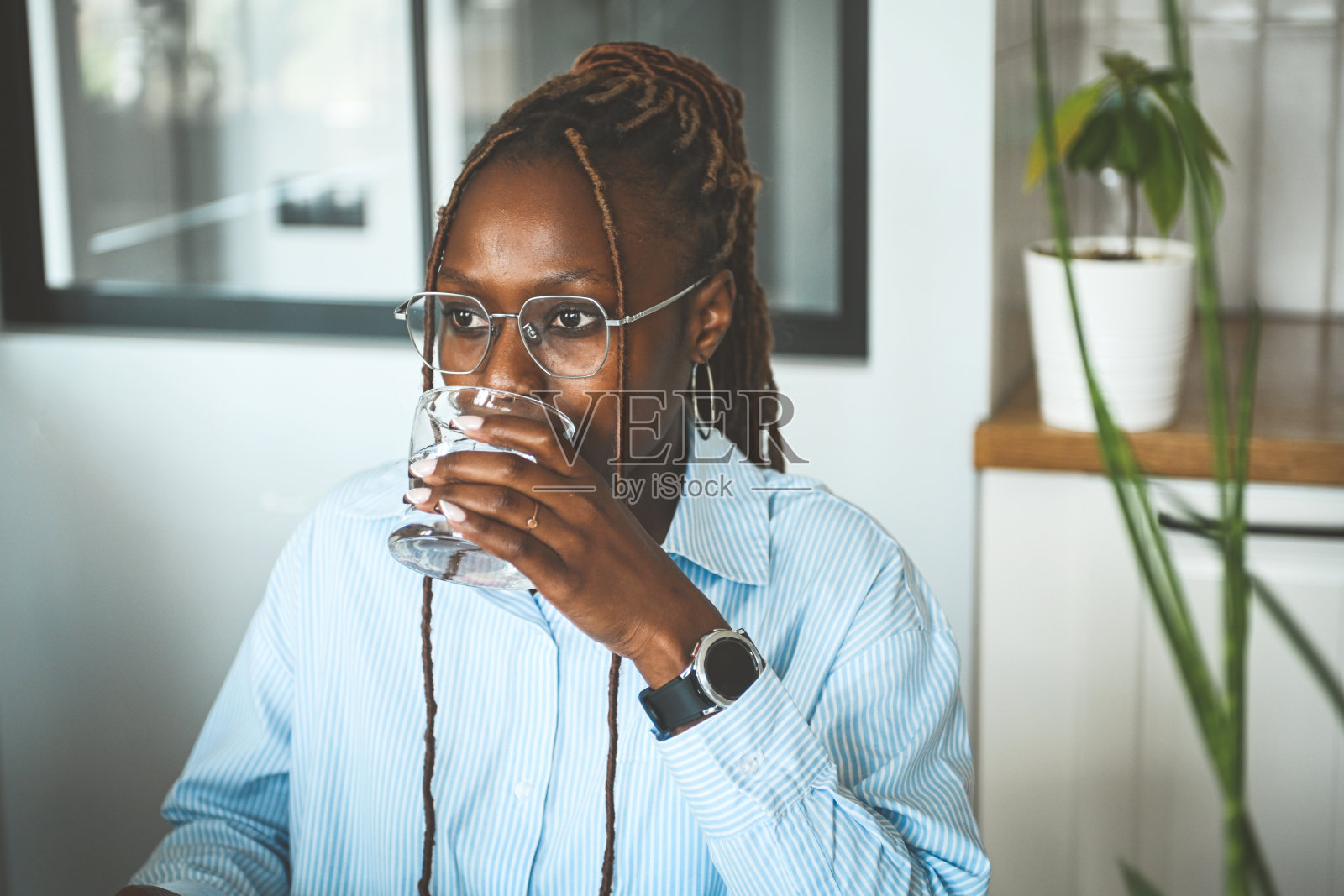 年轻女性正在喝水,手中拿着一杯水照片摄影图片