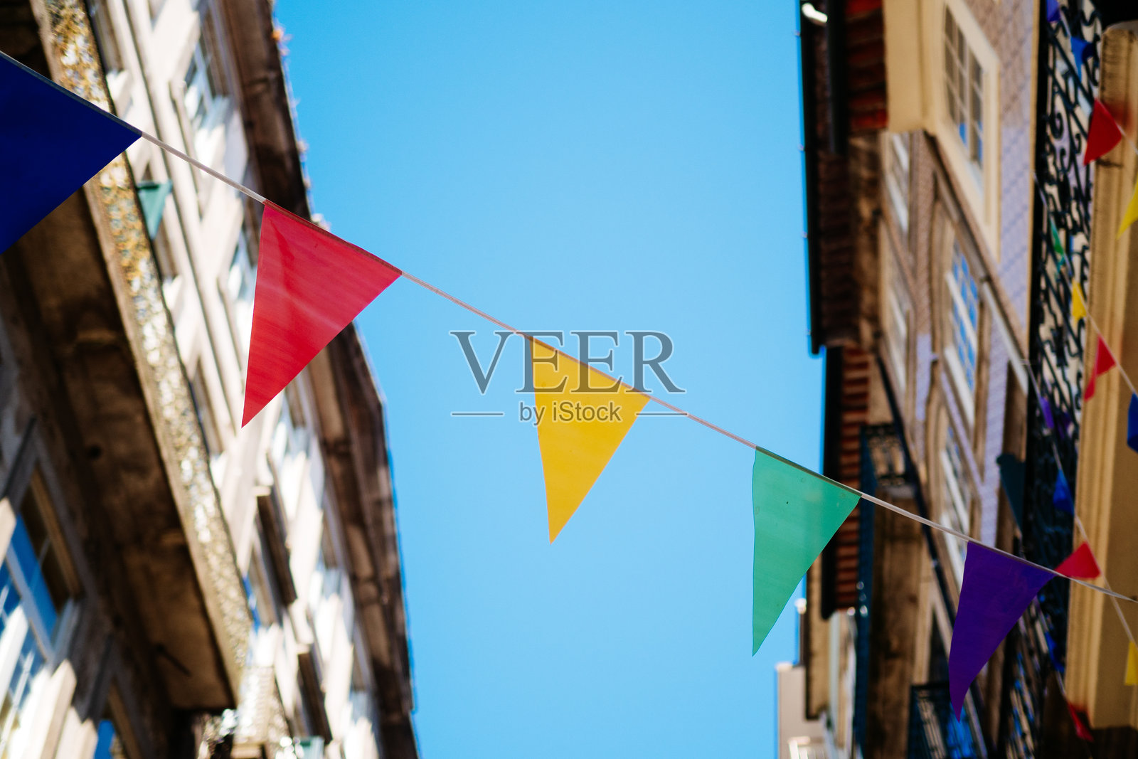 低角度视图,彩旗悬挂在建筑物之间,背景是晴朗的蓝天照片摄影图片