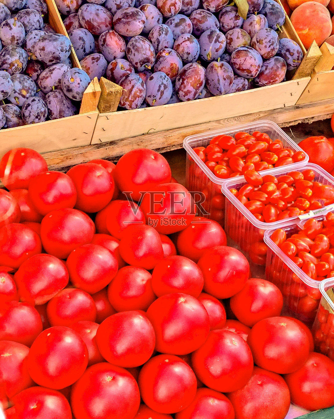 市场上新鲜、明亮的产品有李子、西红柿和草莓。柜台上色彩缤纷的蔬菜和水果组合,竖版。照片摄影图片