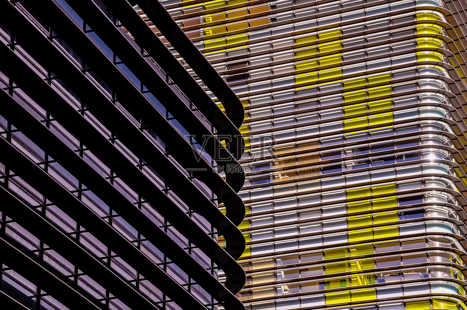 一栋有很多窗户的建筑,墙壁上有黄色和蓝色的条纹。照片摄影图片