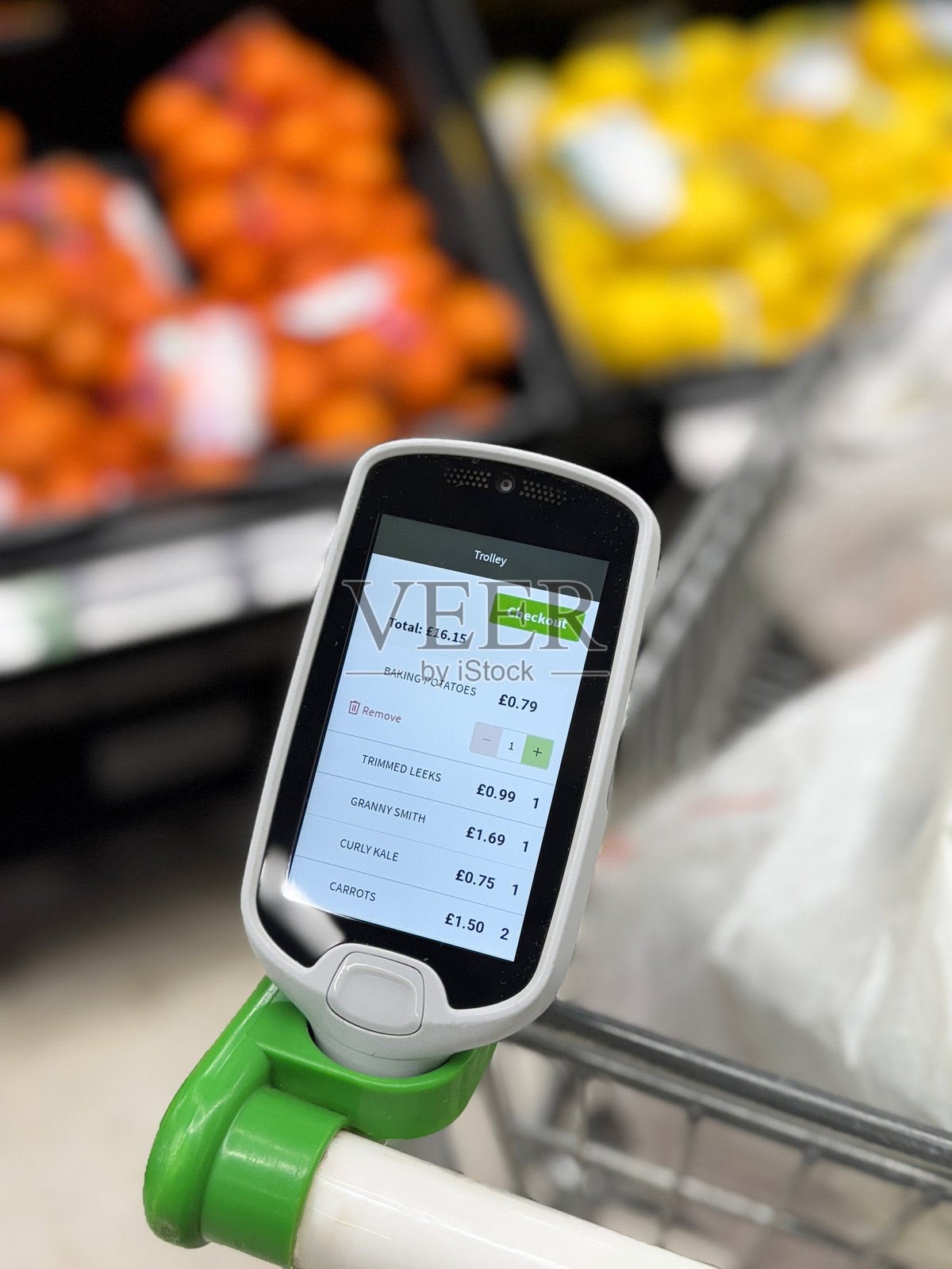 超市便携式价格扫描仪在购物车把手支架上,在食品杂货通道购物,商品清单、商品价格、运营成本总额、水果和蔬菜展示架,橙色和柠檬柑橘水果背景,焦点在前台照片摄影图片