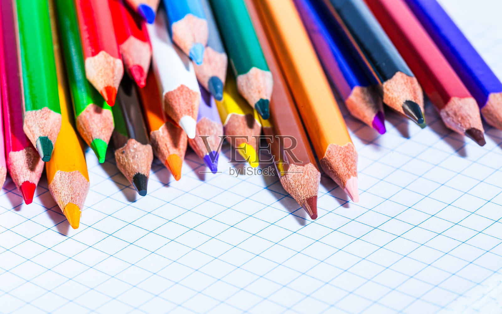 色彩斑斓的光谱:一排彩色铅笔放在一张纸上。一排彩色铅笔静静地放在一张纸上。照片摄影图片