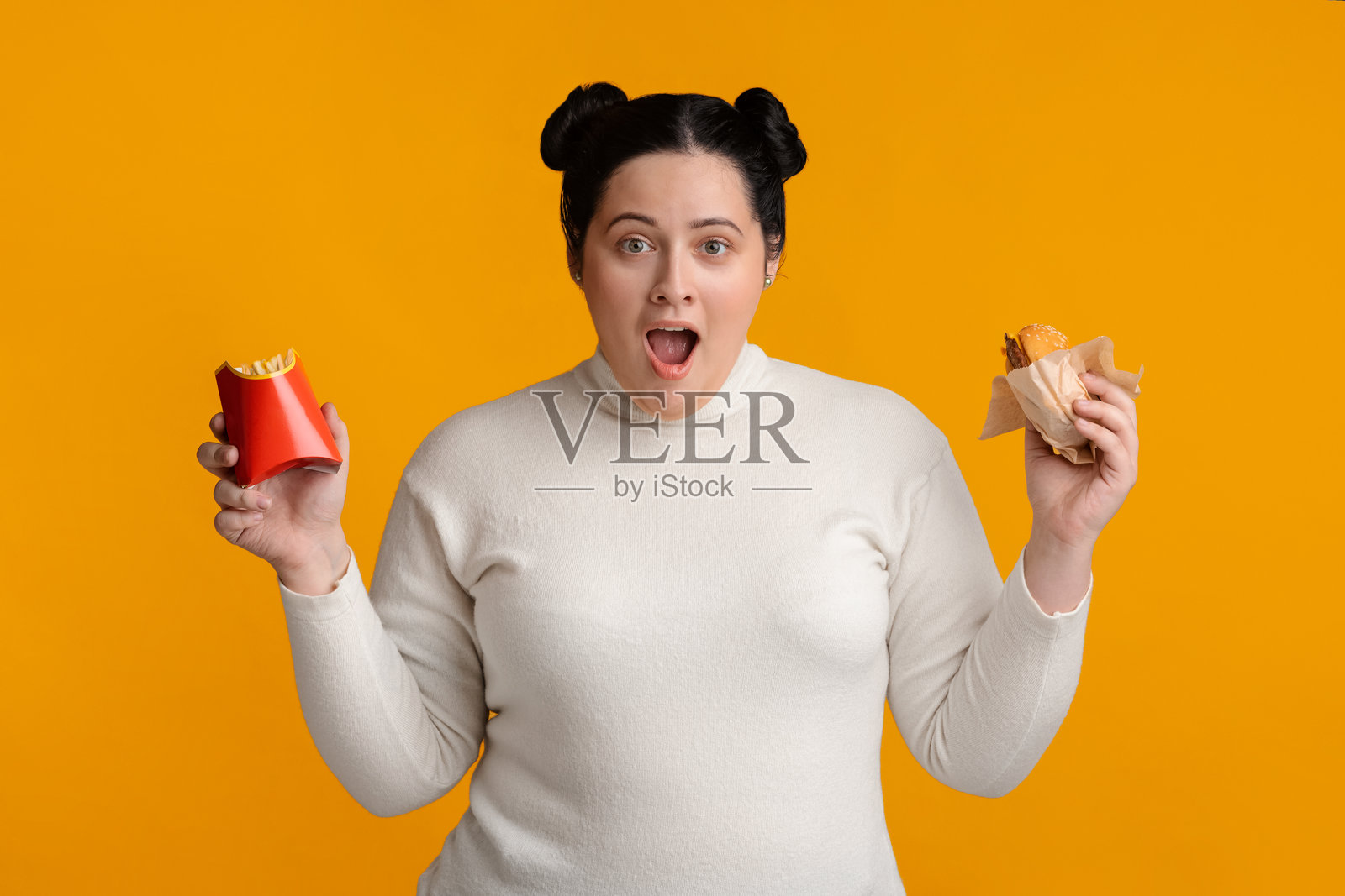 手拿汉堡和炸薯条的吃惊的超重女孩照片摄影图片