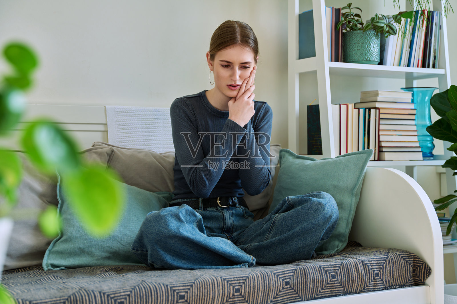 在家坐在沙发上牙疼的年轻女孩照片摄影图片