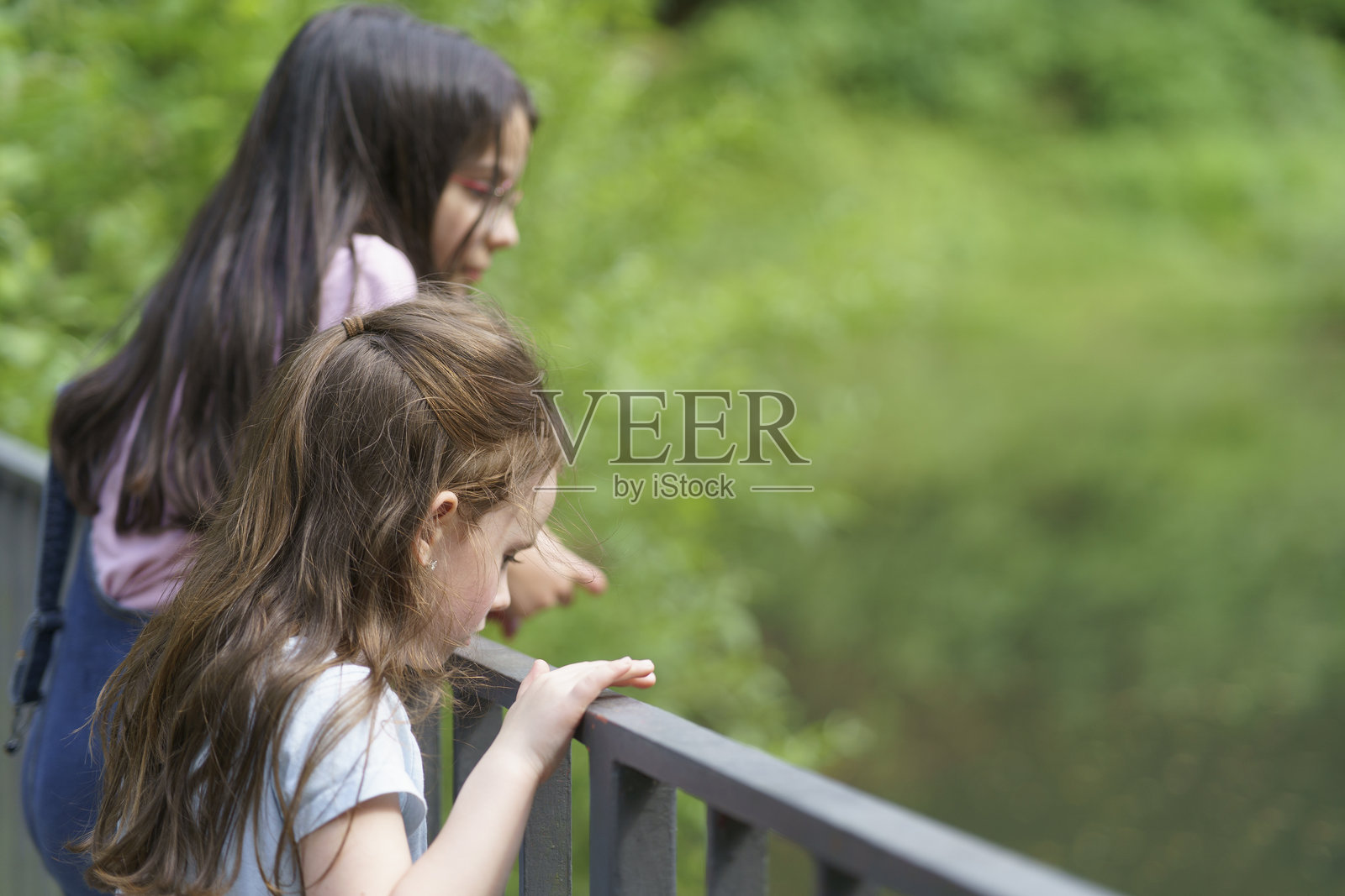 两个小女孩在池塘附近玩耍。儿童户外乐趣的概念照片摄影图片