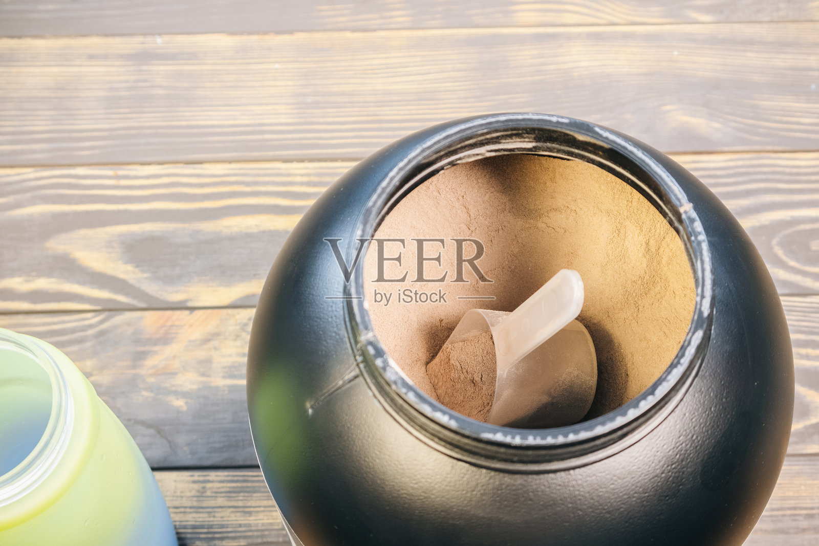 黑色容器中的增重蛋白粉,适合肌肉增长。健康的运动营养。特写勺子,确保正确剂量。照片摄影图片