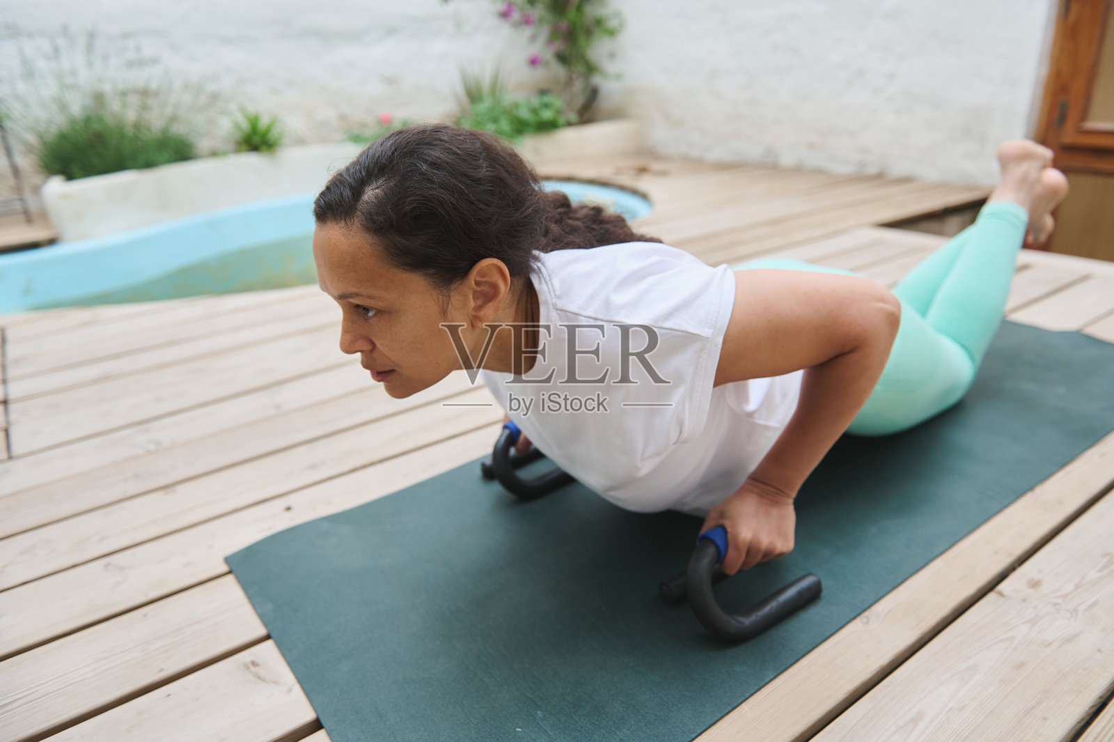 女性在户外瑜伽垫上练习俯卧撑,进行健身锻炼照片摄影图片
