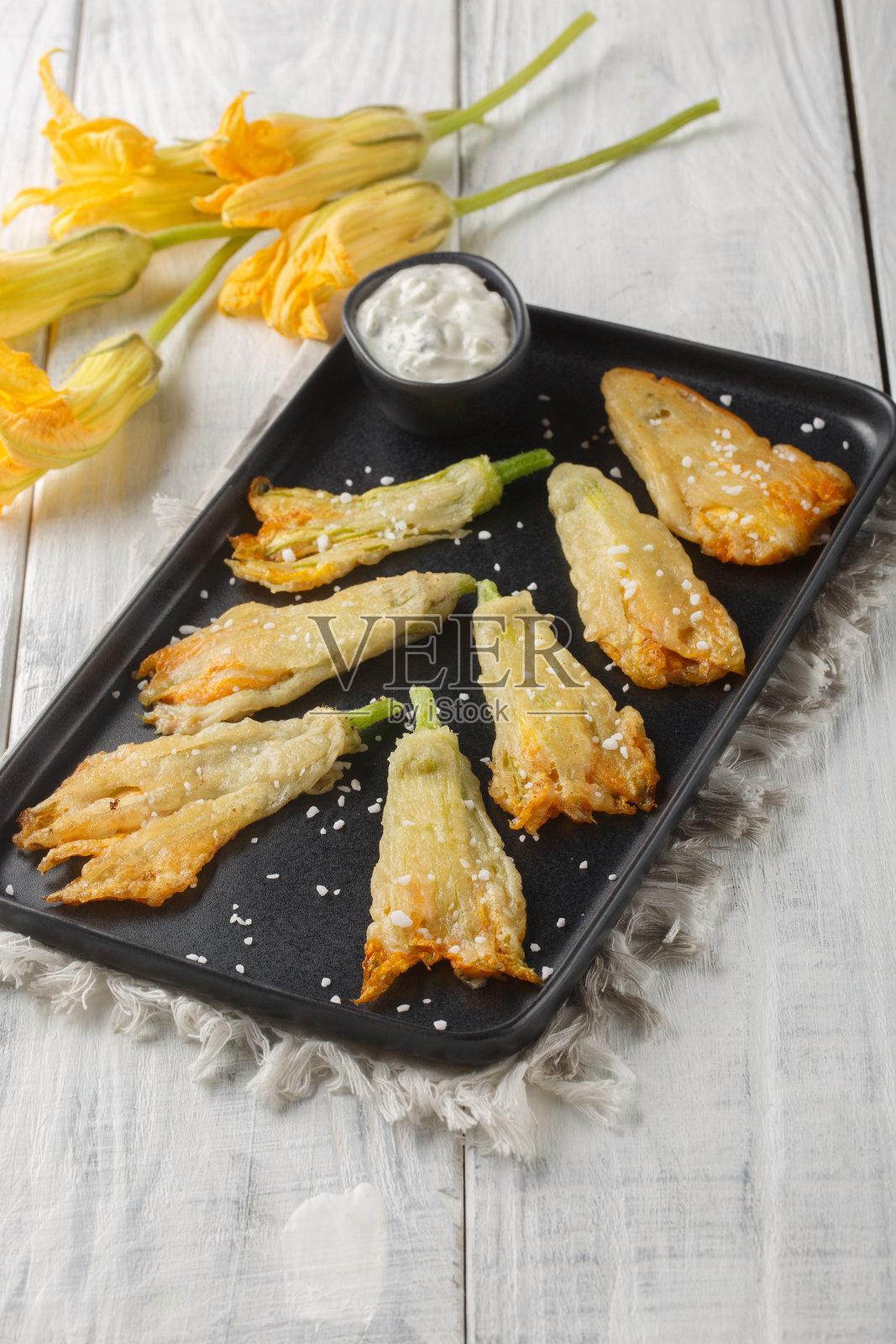 美味的炸面包裹的西葫芦花,里面填满了意大利乳清干酪,特写在盘子里。竖版照片摄影图片