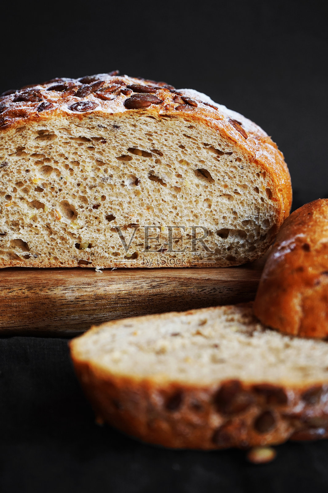 新鲜的谷物面包旁边放着切好的面包片,放在木板上照片摄影图片