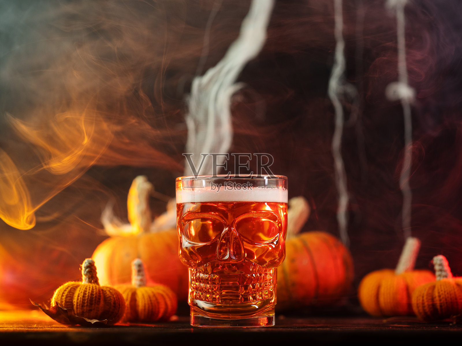 万圣节横幅,带有啤酒杯骷髅。黑暗烟雾背景中有南瓜。照片摄影图片